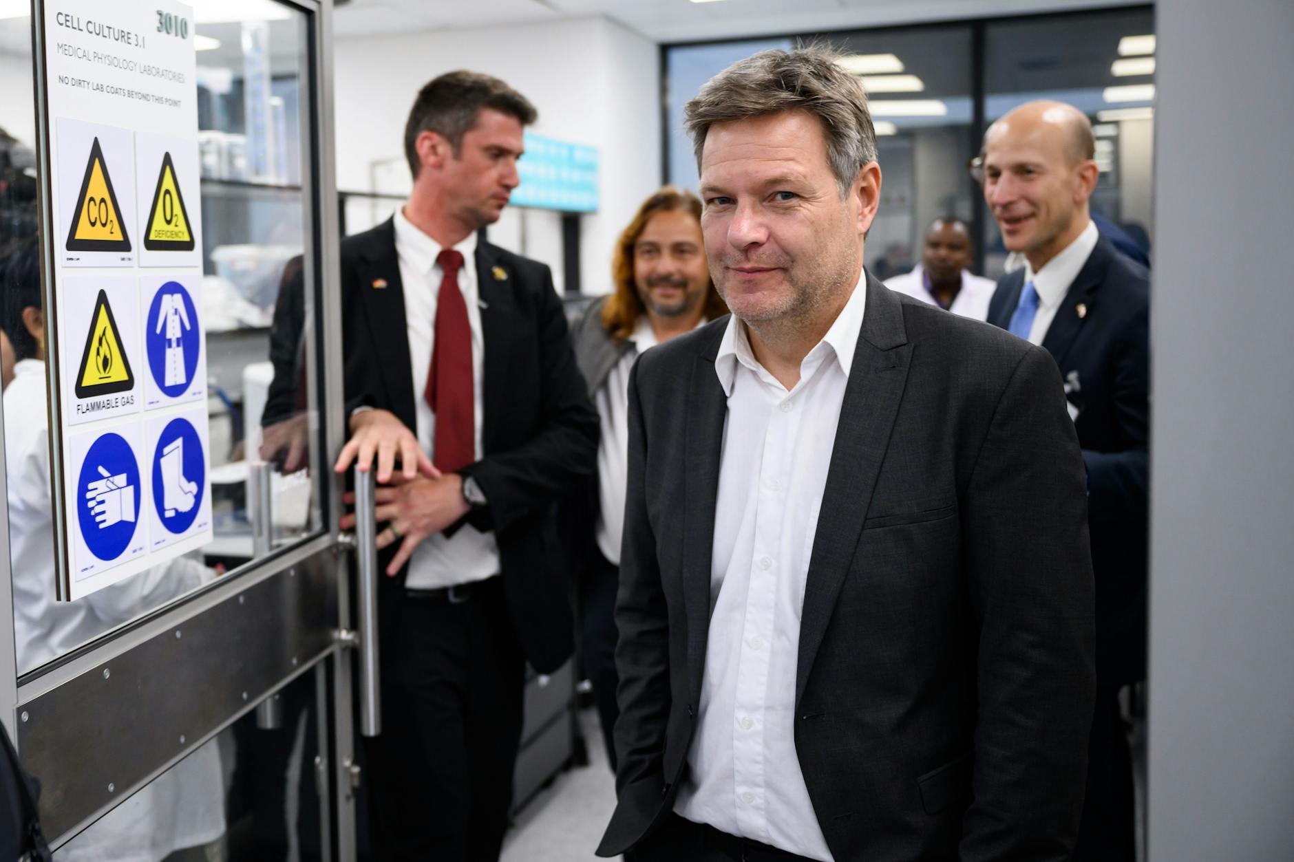 Robert Habeck lächelt, während er durch das Biomedical Research Institute (BMRI) in Kapstadt, Südafrika, geführt wird.