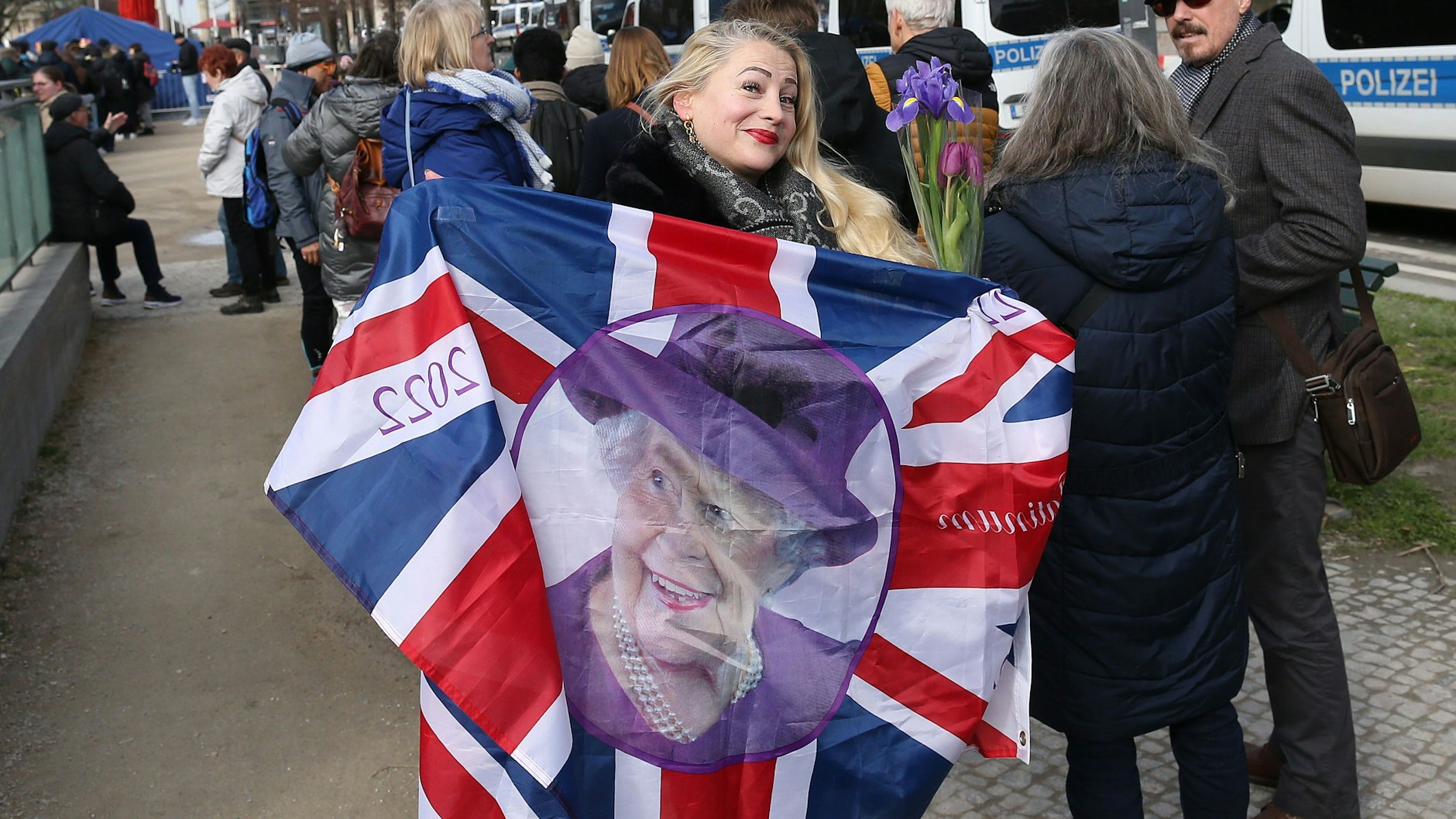 Erena Wysozzanska (39) aus Wilmersdorf begrüßt König Charles III. mit der Erinnerungsfahne vom 70. Thronjubiläum seiner Mutter, der im vergangenen Jahr verstorbenen Queen.