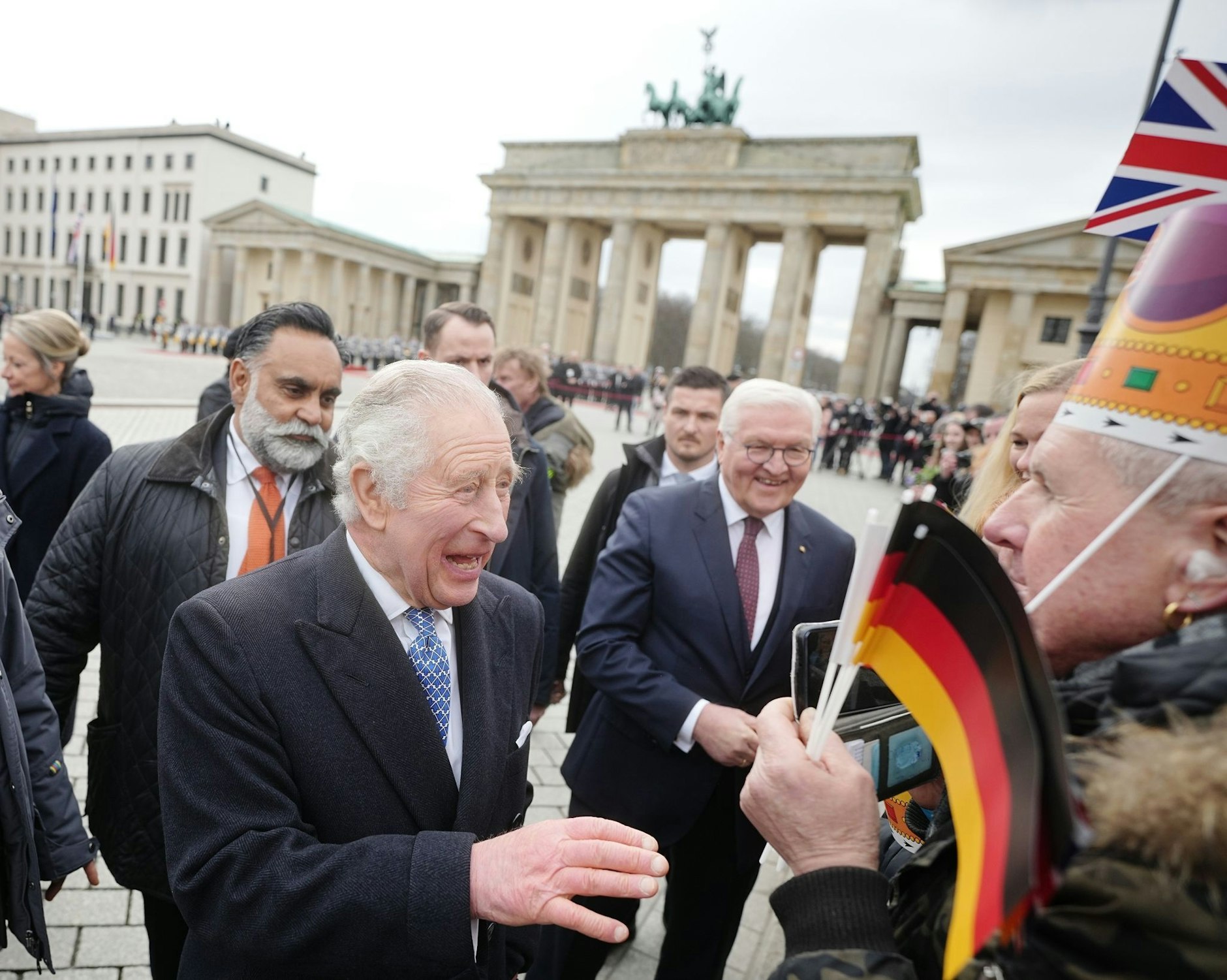 König Charles III. von Großbritannien schüttelt Hände. Zusammen mit Bundespräsident Frank-Walter Steinmeier genießt er den Smalltalk mit den Besuchern.