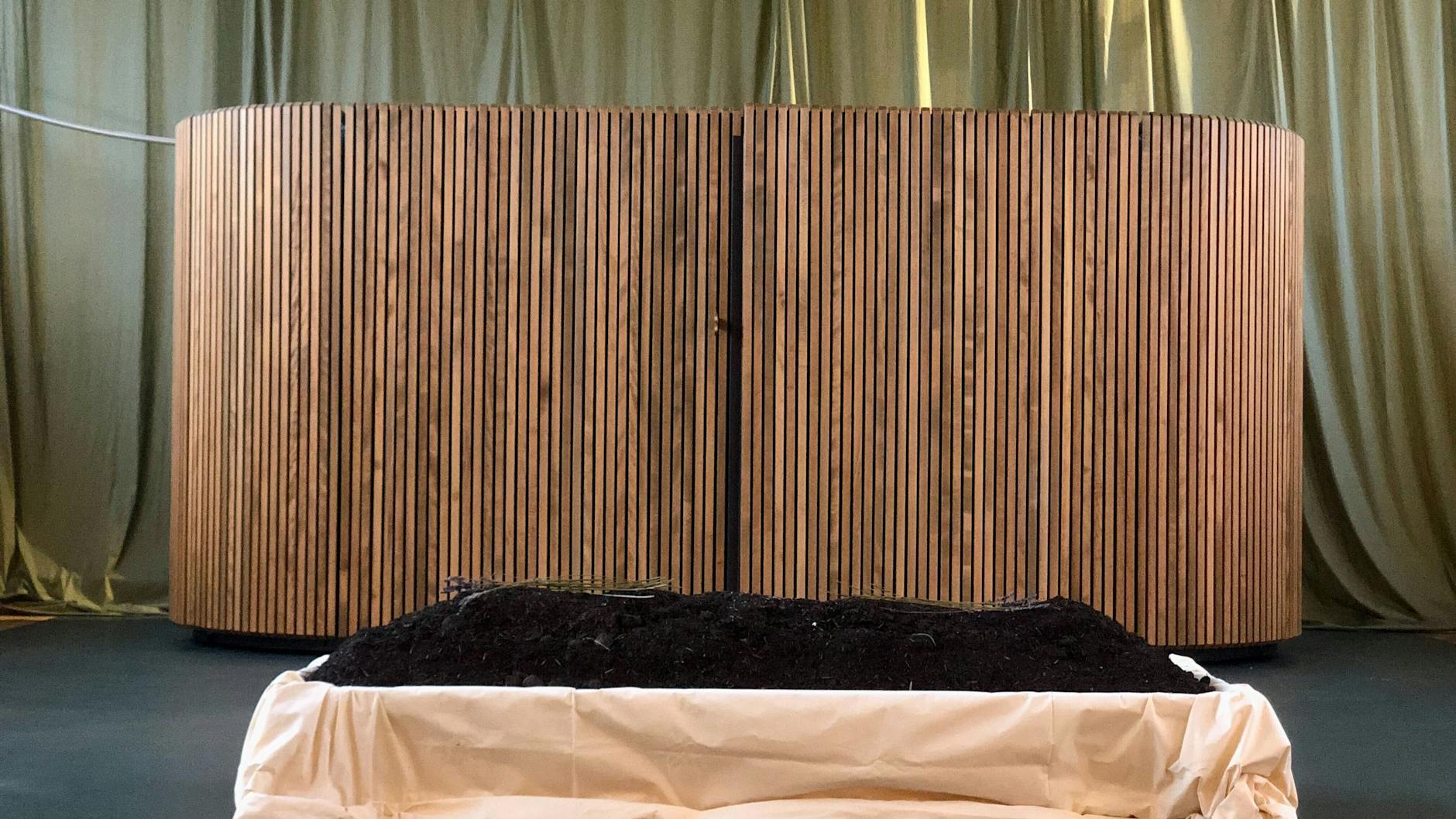 In der hölzernen Wabe befindet sich ein Behälter, Kokon genannt. In diesem wird aus dem Körper binnen 40 Tagen neue Erde.