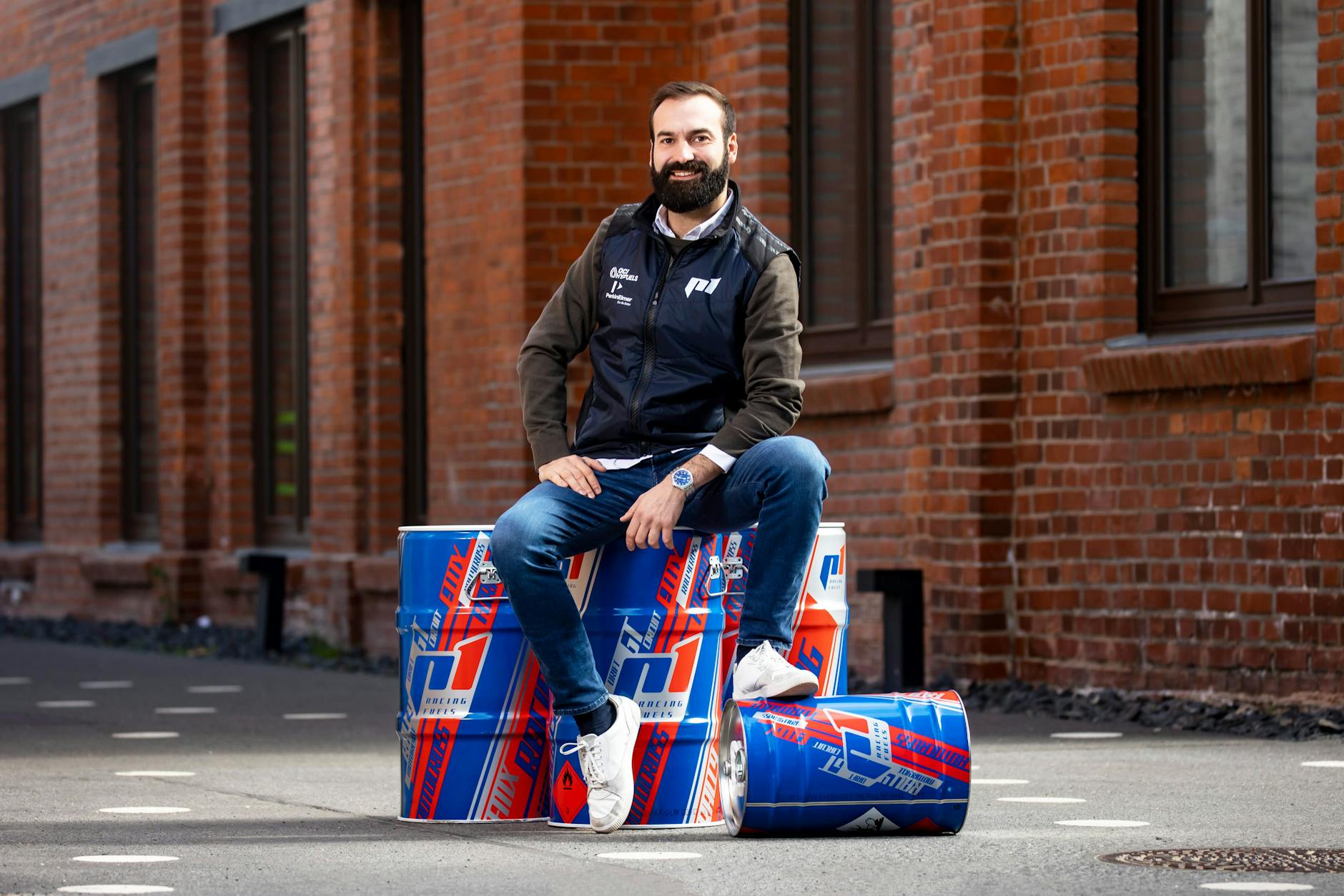 Geschäftsführer von P1 Performance Fuels Martin Popilka posiert auf den Fässern für E-Fuels.