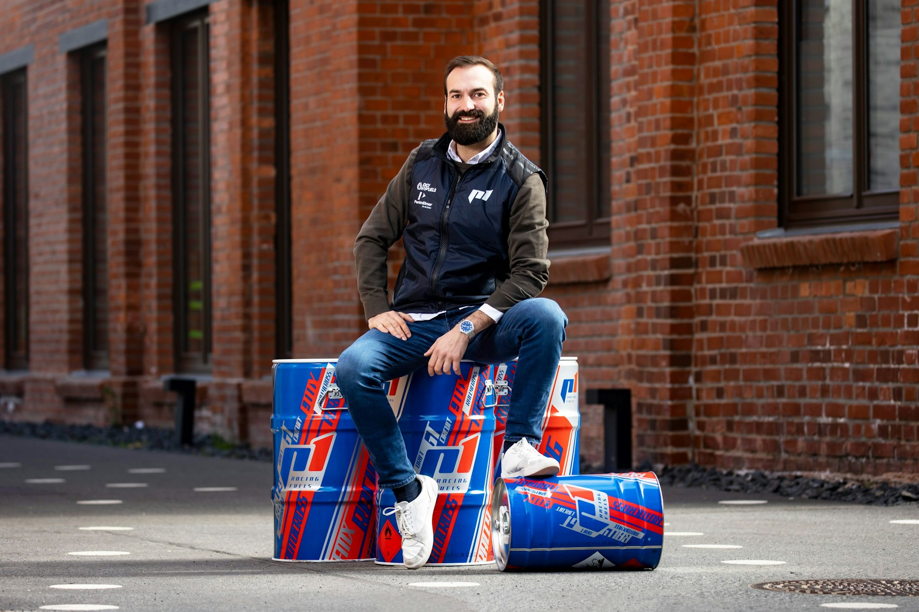 Geschäftsführer von P1 Performance Fuels Martin Popilka posiert auf den Fässern für E-Fuels.