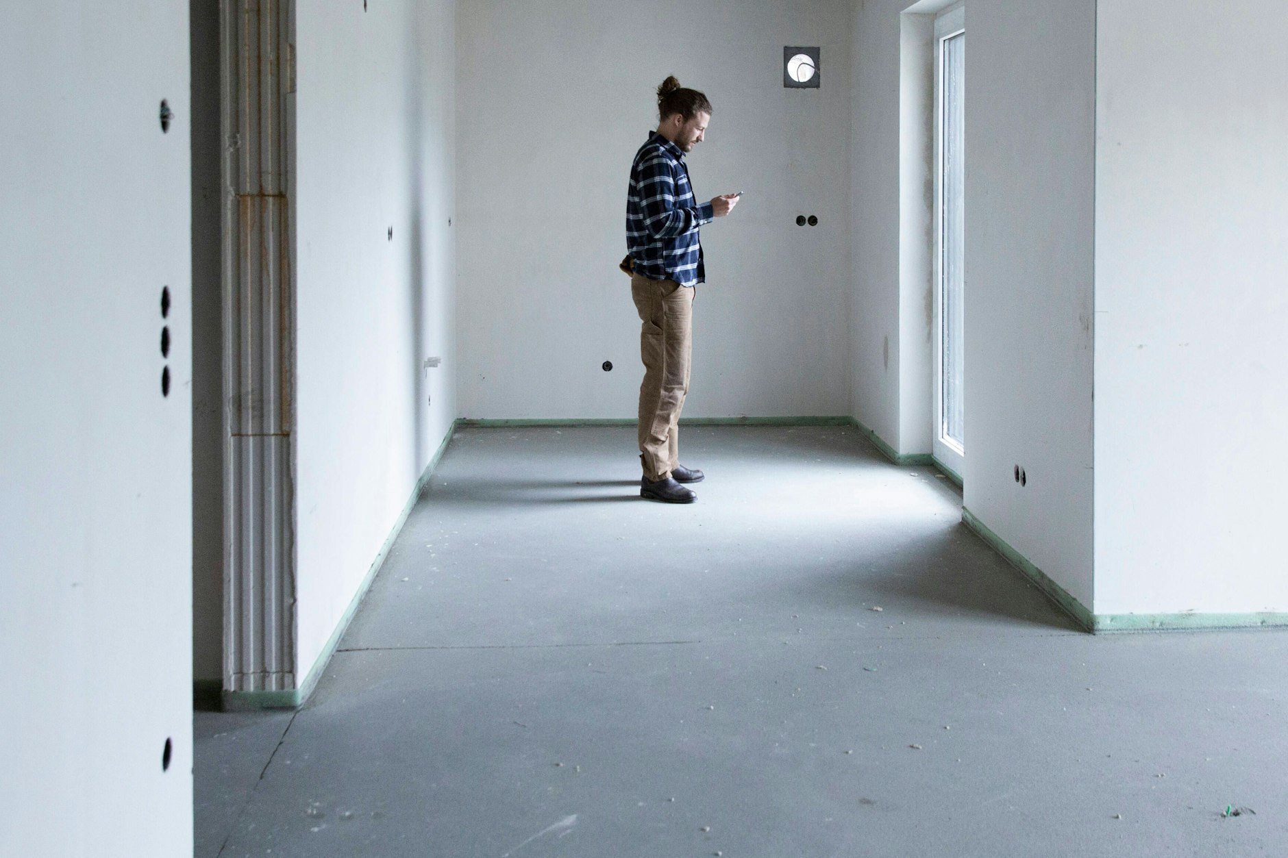 Bauarbeiter steht in leerem Haus auf einer Baustelle.
