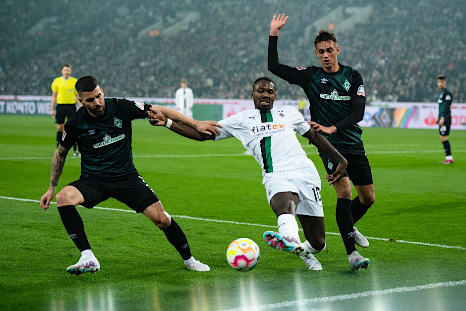 Gladbachs Marcus Thuram (M) kämpft mit Bremens Anthony Jung (l) und Fabio Chiarodia um den Ball.  