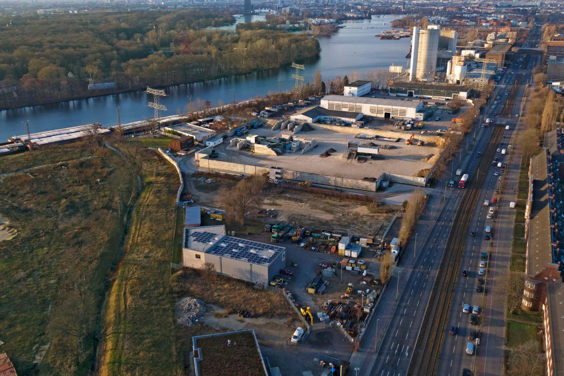 Hier will die Firma Archigon ihr Spreewerk bauen: In etwa zwischen der vorderen vor dem Zementwerk querstehenden Hallen bis zur Tischlerei Maßwerk unten im Bild. Das leicht abgewinkelte Gebäude mit Solardach wird abgerissen, die ummauerte Baustoff-Recyclinganlage wird wegen heranschreitenden Rentenalters von den Eigentümern aufgegeben.  Rechts an der Köpenicker Chaussee die Gaswerkssiedlung.