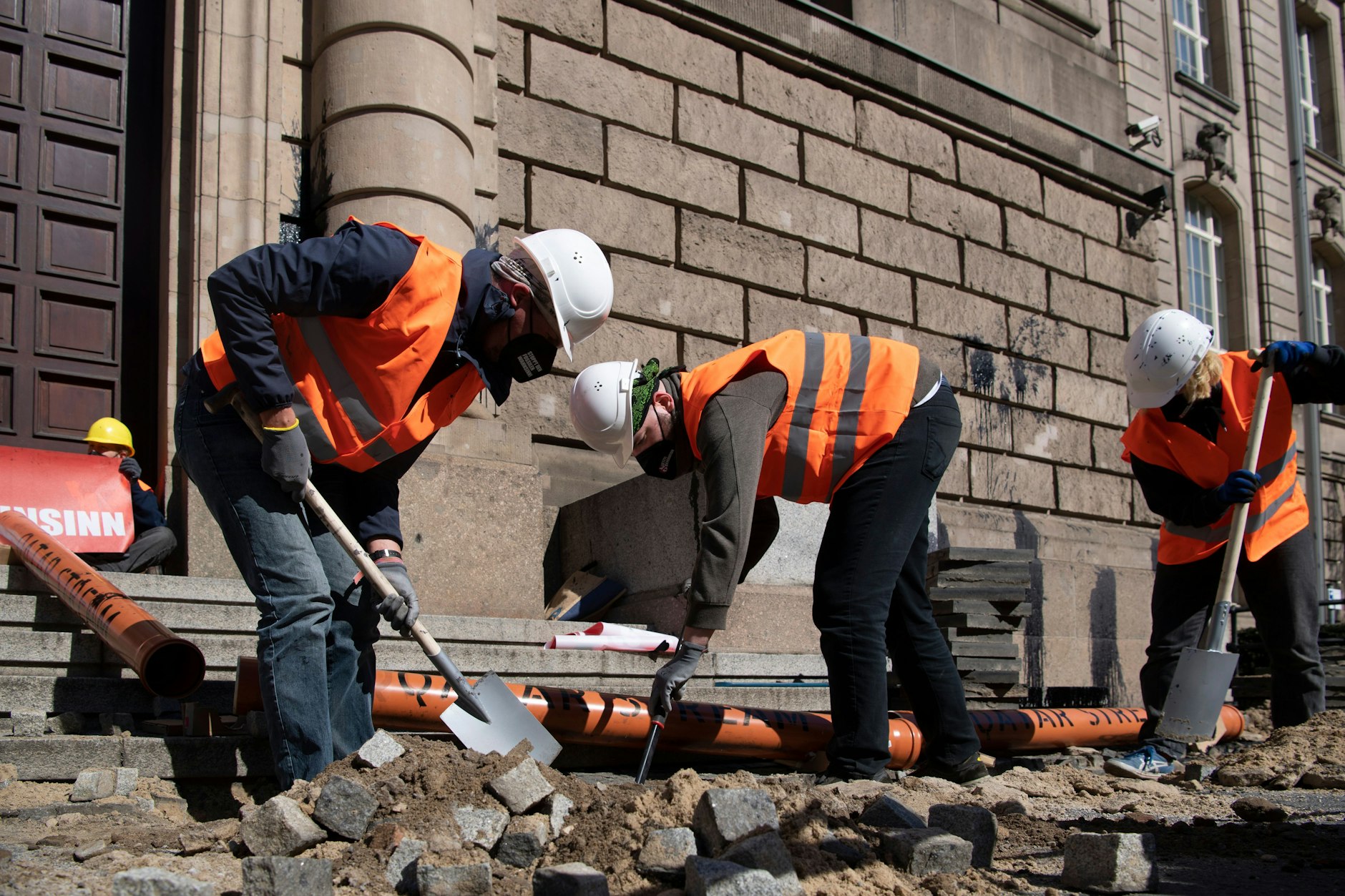 Nicht jeder, der wie ein Bauarbeiter aussieht, ist auch einer. Aktivisten der Gruppe Letzte Generation reißen vor dem Bundeswirtschaftsministerium den Gehweg auf.
