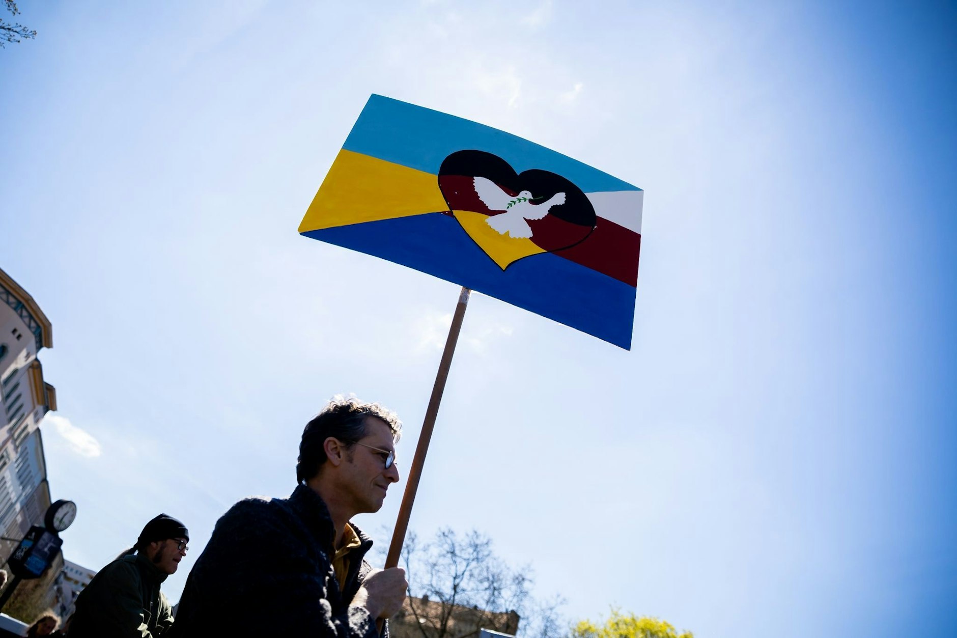 Ein Mann trägt bei einem Ostermarsch unter dem Motto „Die Waffen nieder!“ am Oranienplatz in Berlin ein Schild mit Friedenstaube.&nbsp;