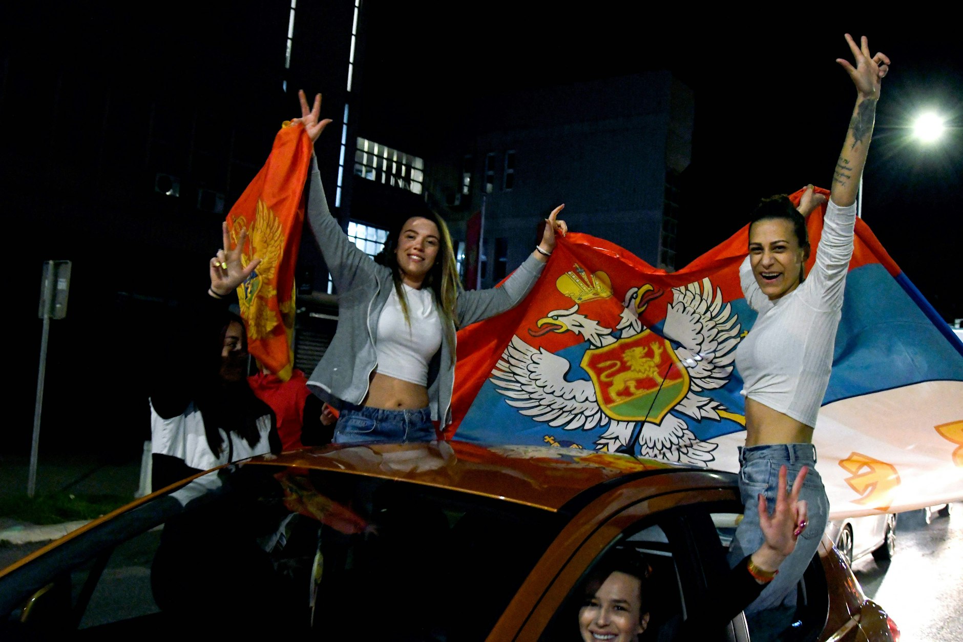 Unterstützer des neuen Präsidenten Milatović halten die montenegrinischen Flaggen.