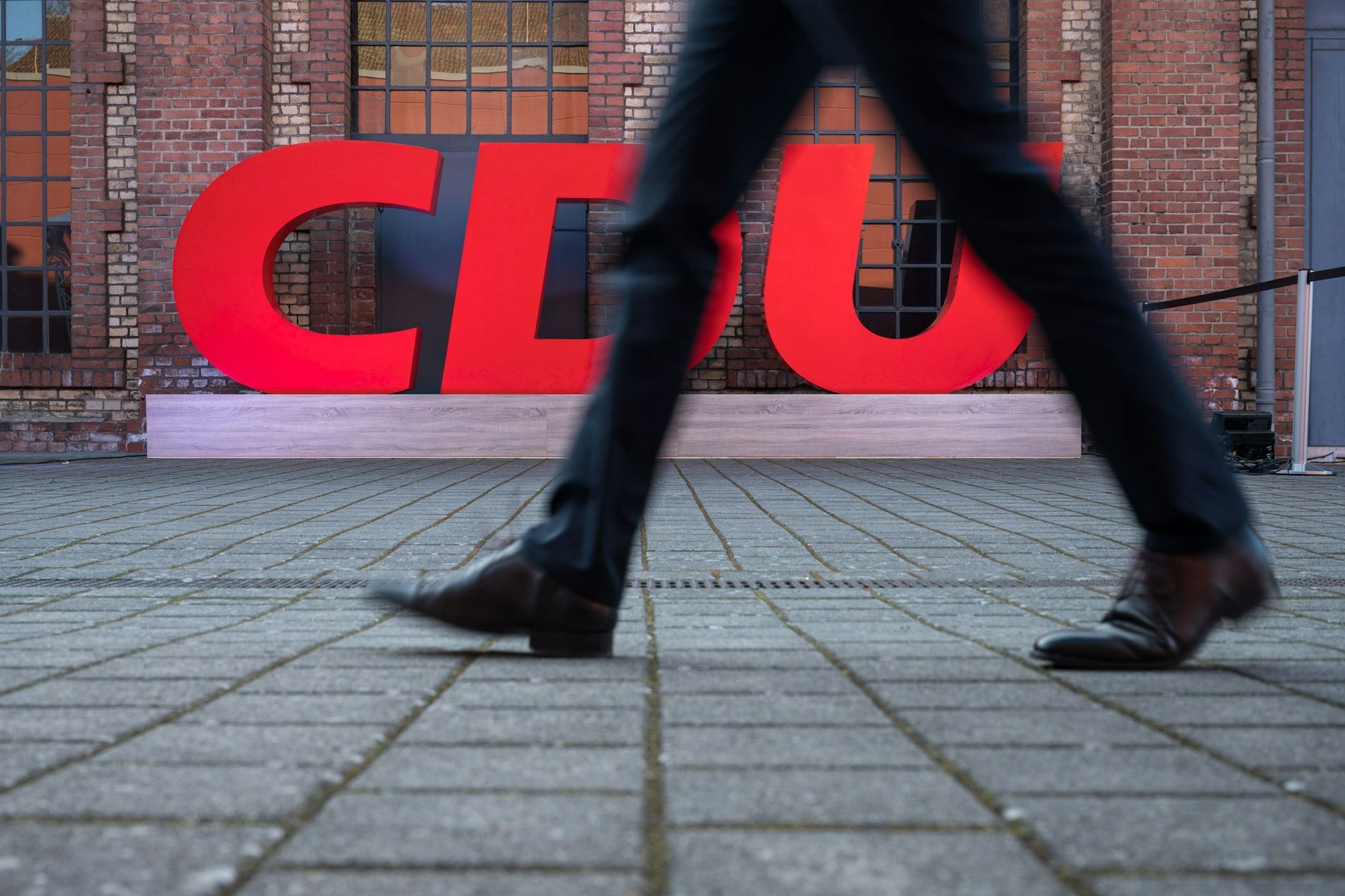 Ein Passant geht an einem Logo der CDU vorbei.  