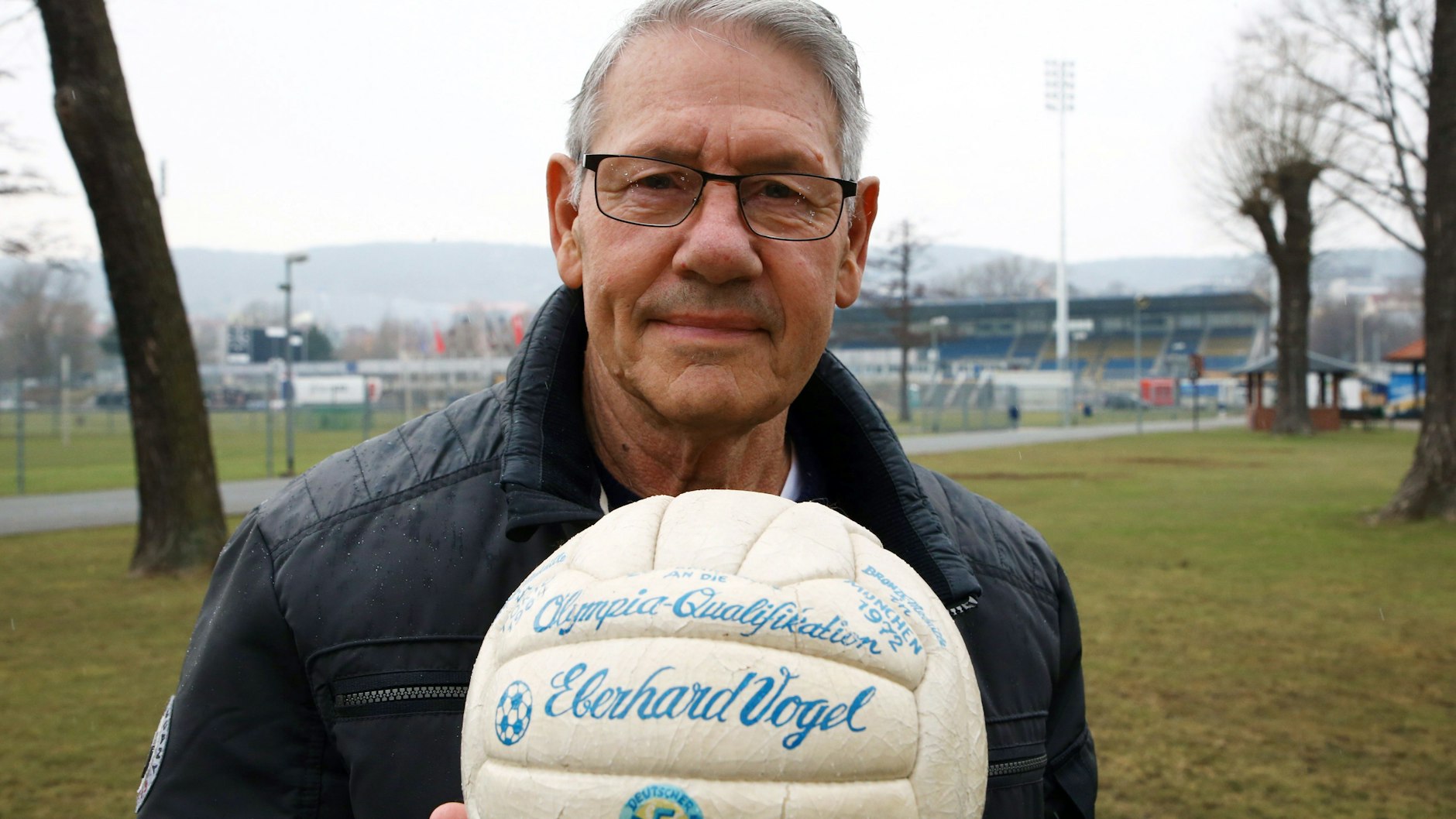 Ein Foto aus dem März 2018: Eberhard Vogel steht mit dem Originalball der Olympiaqualifikation von 1972 auf dem Gelände des Ernst-Abbe-Sportplatzes in Jena.