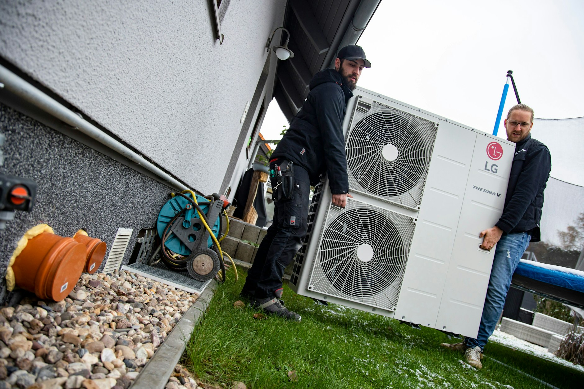 Monteur Daniele Russo und Gebietsleiter Christian Beggerow der Firma Thermondo transportieren eine Wärmepumpe für die Montage in einem Haus in Berlin am 22. November 2022.