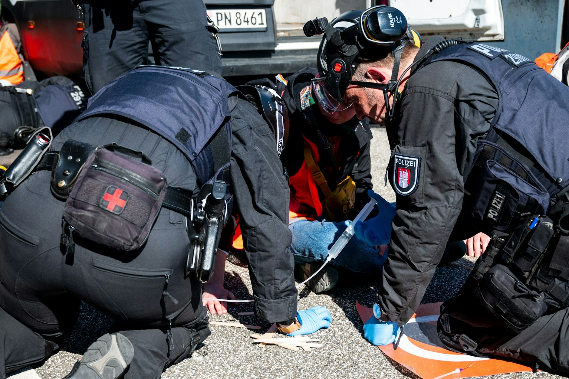 Polizisten versuchen einen Klima-Aktivisten von der Fahrbahn zu lösen.