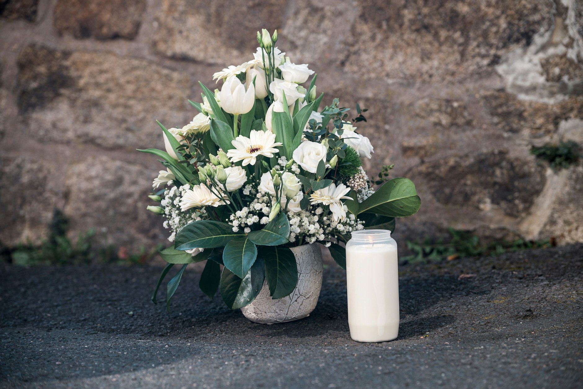 Wunsiedel: Ein Strauß Blumen und eine Kerze wurden an einer Mauer vor dem Kinder- und Jugendhilfezentrum niedergelegt. Ein zehnjähriges Mädchen war in dem Kinder- und Jugendhilfezentrum aufgefunden worden.&nbsp;