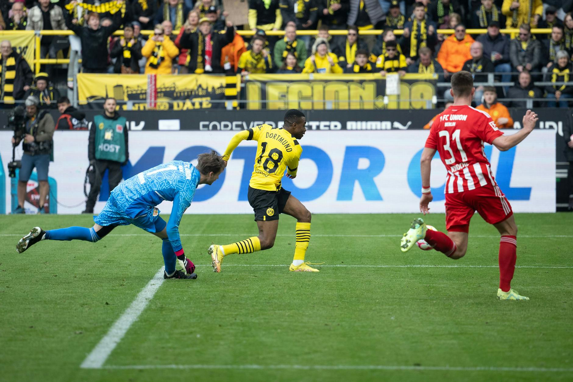 Dortmunds Youssoufa Moukoko erzielt das 2:1 gegen Torhüter Frederik Ronnow und Robin Knoche von Union Berlin.