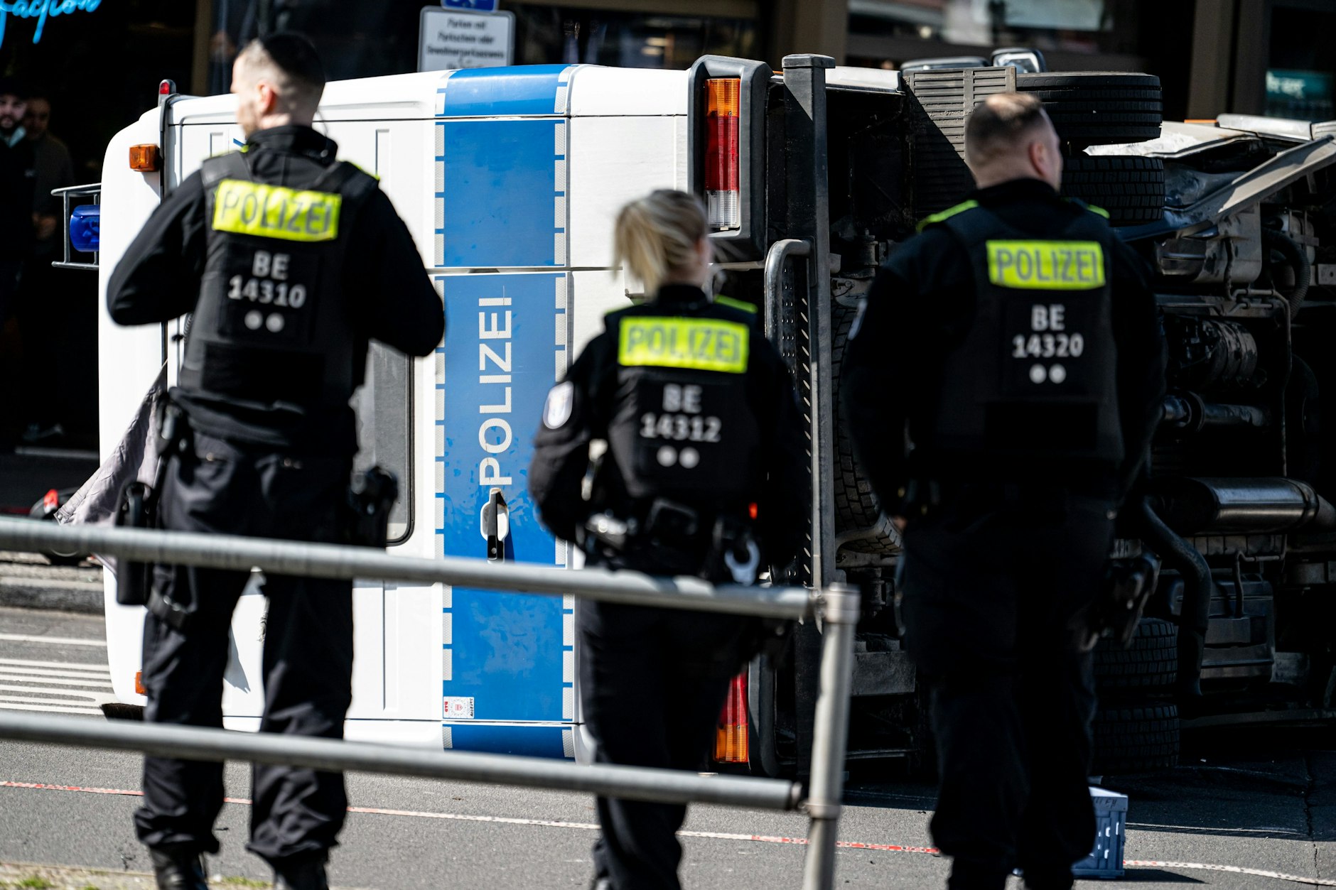 Eine Polizistin und zwei Kollegen vor dem umgekippten Polizeifahrzeug.