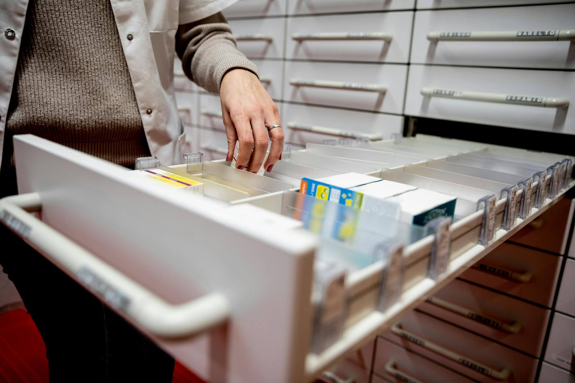 Eine Apothekerin greift in einer Apotheke in eine Medikamentenschublade. 