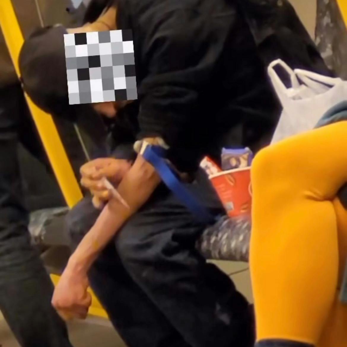 Ein Mann setzt sich in einer Berliner U-Bahn eine Spritze am Arm.