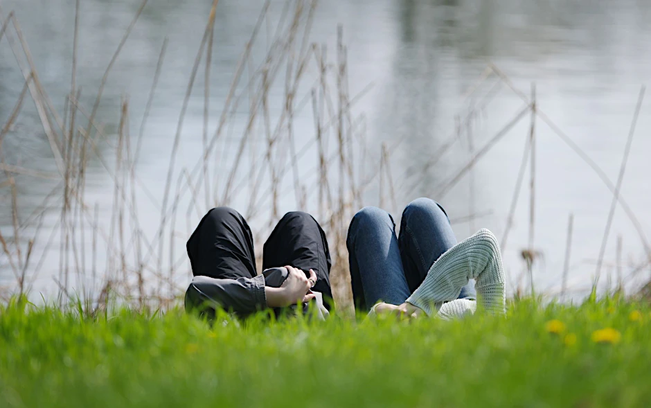 Menschen liegen am Ostermontag bei Sonnenschein auf einer Wiese im Clara-Zetkin-Park in Leipzig.  