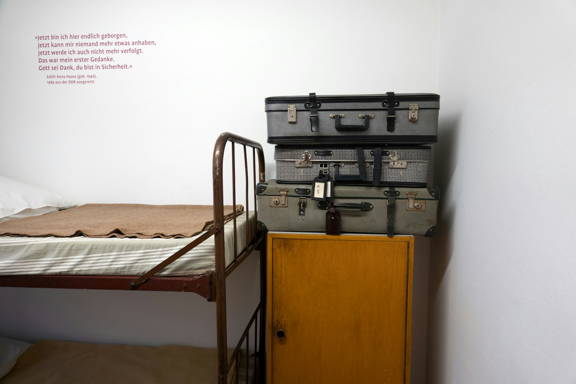 Koffer liegen in einem Zimmer in der Erinnerungsstätte Notaufnahmelager Berlin-Marienfelde auf einem Schrank.