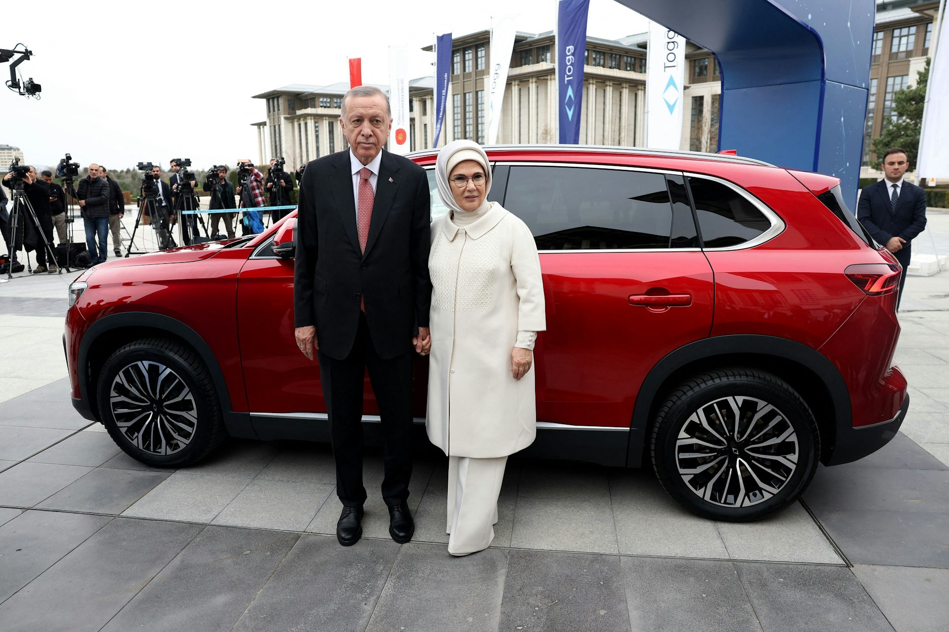 Erdogan, hier mit Ehefrau Emine, guckt inzwischen sogar dann grimmig, wenn er das erste türkische E-Auto Togg T10X vor seinem in ein Naturschutzgebiet gepflanzten Palast vorstellt.