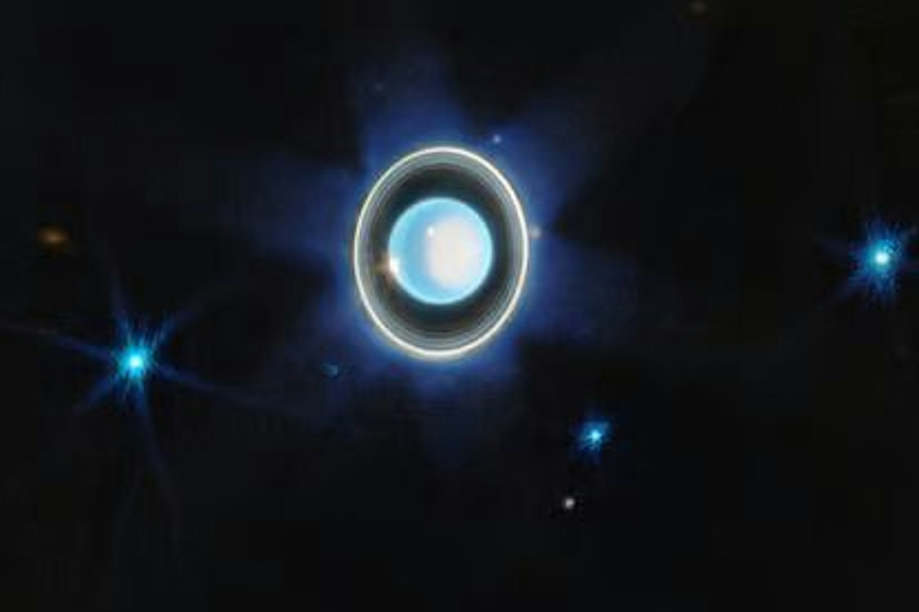 Dieses neue Bild vom Uranus zeigt den Planeten mit seinen Ringen, dazu einige seiner 27 bekannten Monde. Auf dem Planeten ist die weiß schimmernde Polkappe zu sehen, dazu als helle Punkte zwei Wolken.