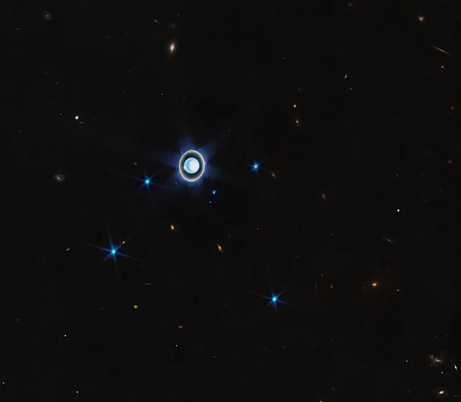 Dieses neue Bild vom Uranus zeigt den Planeten mit seinen Ringen, dazu einige seiner 27 bekannten Monde. Auf dem Planeten ist die weiß schimmernde Polkappe zu sehen, dazu als helle Punkte zwei Wolken.