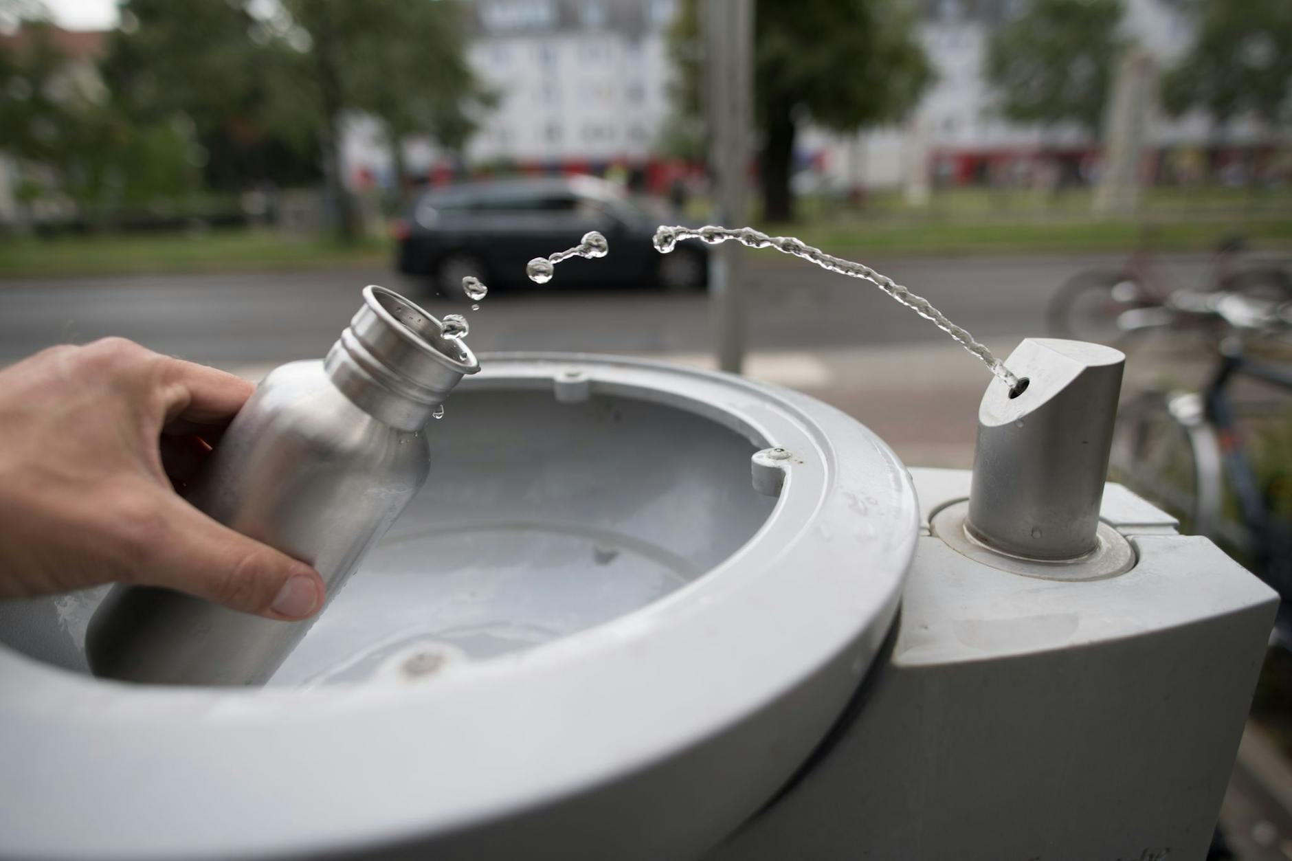 An einem Wasserspender der Berliner Wasserbetriebe füllt sich ein Passant seine Trinkflasche auf.