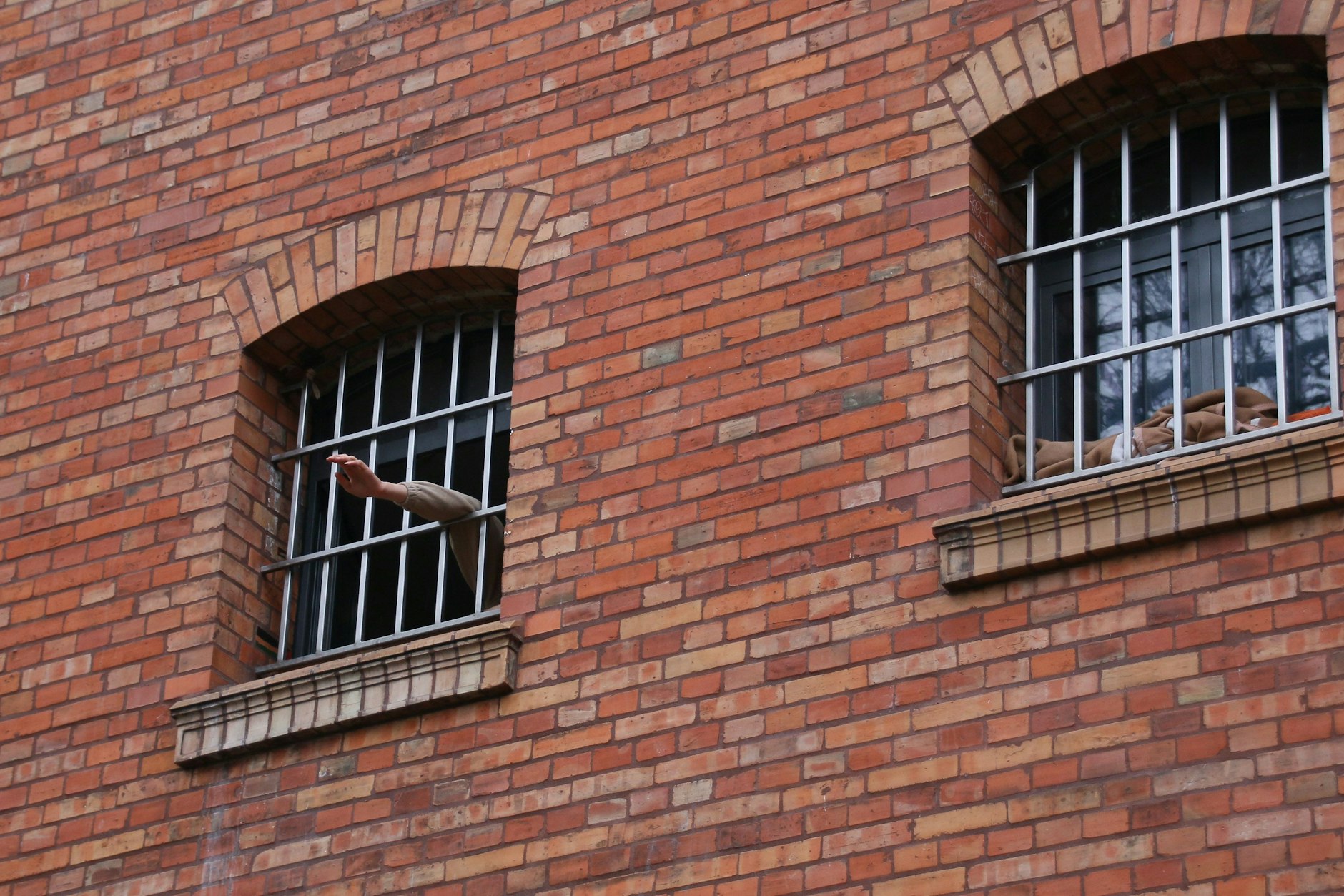 Ein Minderjähriger winkt aus dem vergitterten Zellenfenster der Jugendstrafanstalt Berlin-Plötzensee.