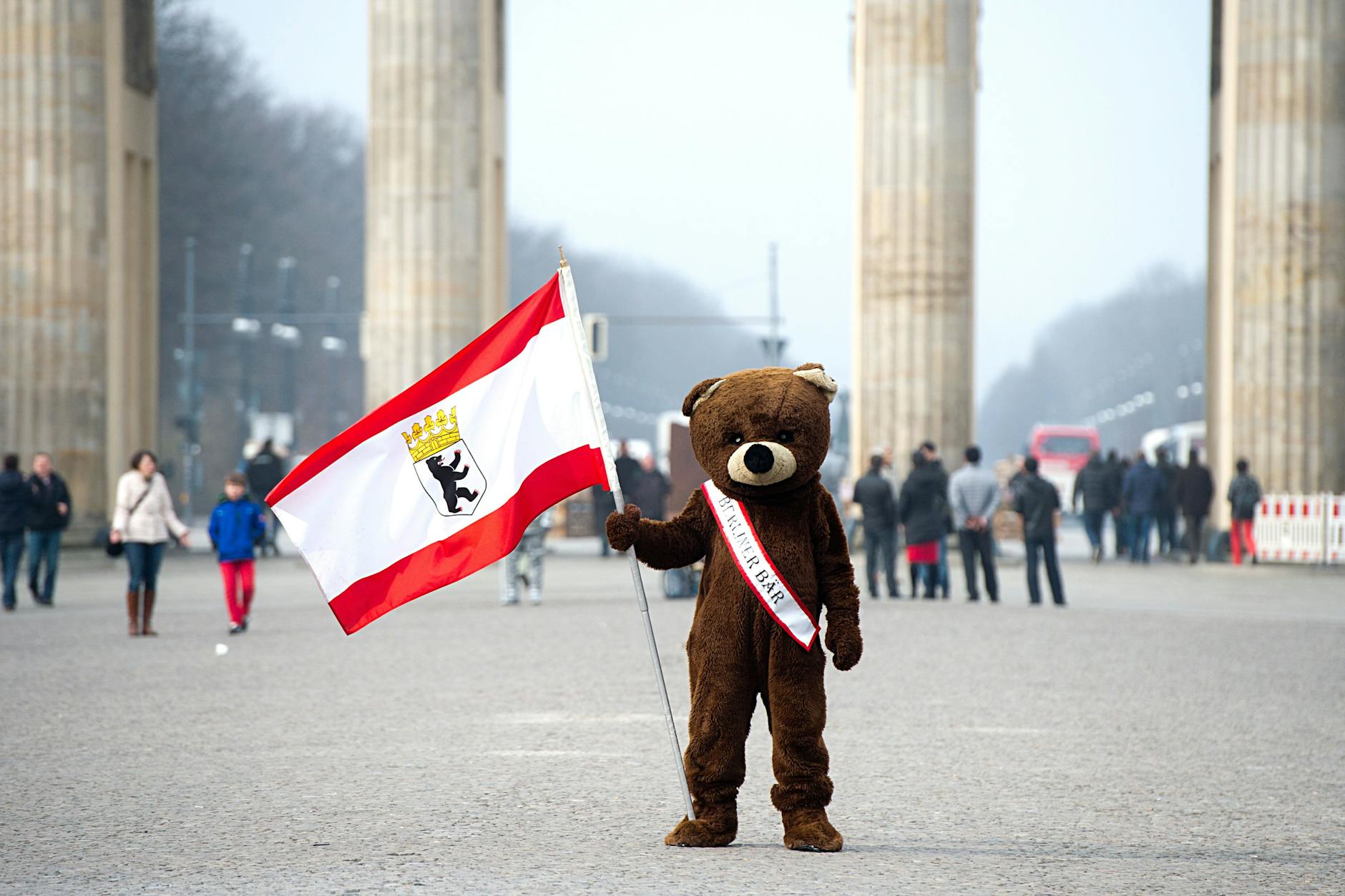 Ein Schausteller steht als Berliner Bär verkleidet vor dem Brandenburger Tor.