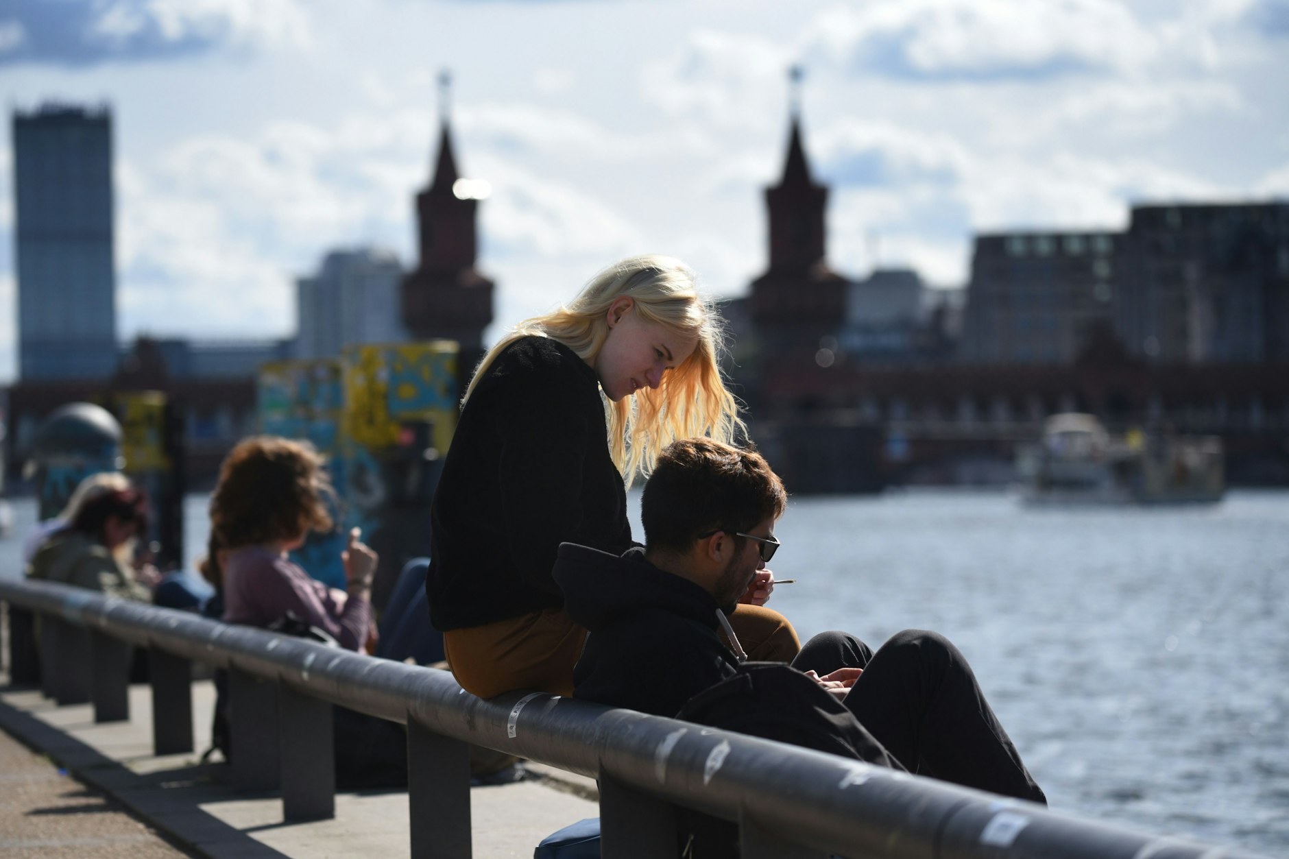 Berlin: Junge Leute sitzen am Ufer – mit Blick auf die Oberbaumbrücke.