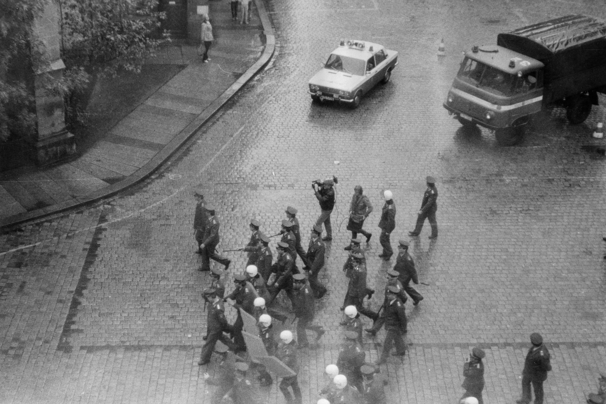 Das Amateurfoto zeigt DDR-Polizisten mit Schlagstöcken und Schutzschilden, die am 7.10.1989 an der Nikolaikirche in Leipzig Demonstranten der DDR-Bürgerbewegung abdrängten und einzelne Personen aus der Gruppe heraus festnahmen. Auch ein Mann mit einer Videokamera begleitete die Uniformierten. Insgesamt blieb es aber friedlich.