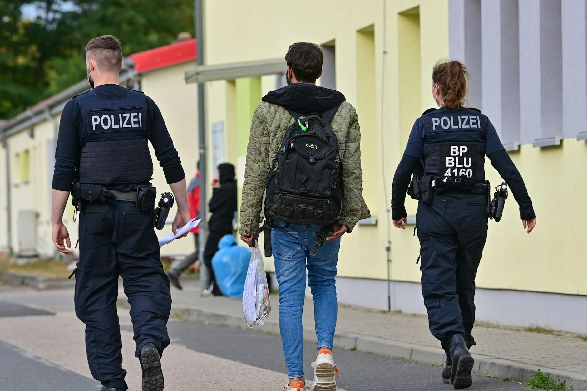Zwei Bundespolizisten begleiten einen Geflüchteten auf dem Gelände der Zentralen Erstaufnahmeeinrichtung für Asylbewerber (ZABH) in Eisenhüttenstadt.