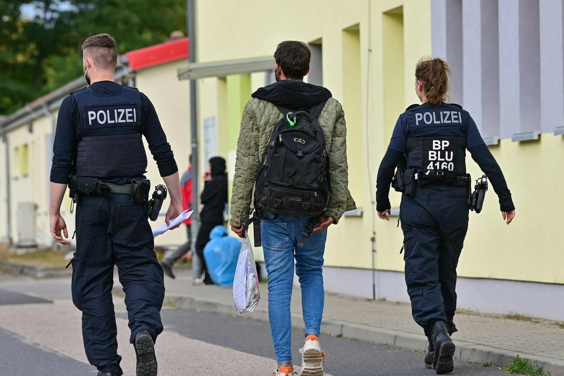 Zwei Bundespolizisten begleiten einen Geflüchteten auf dem Gelände der Zentralen Erstaufnahmeeinrichtung für Asylbewerber (ZABH) in Eisenhüttenstadt.