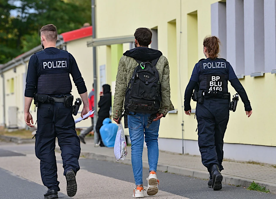Zwei Bundespolizisten begleiten einen Geflüchteten auf dem Gelände der Zentralen Erstaufnahmeeinrichtung für Asylbewerber (ZABH) in Eisenhüttenstadt.