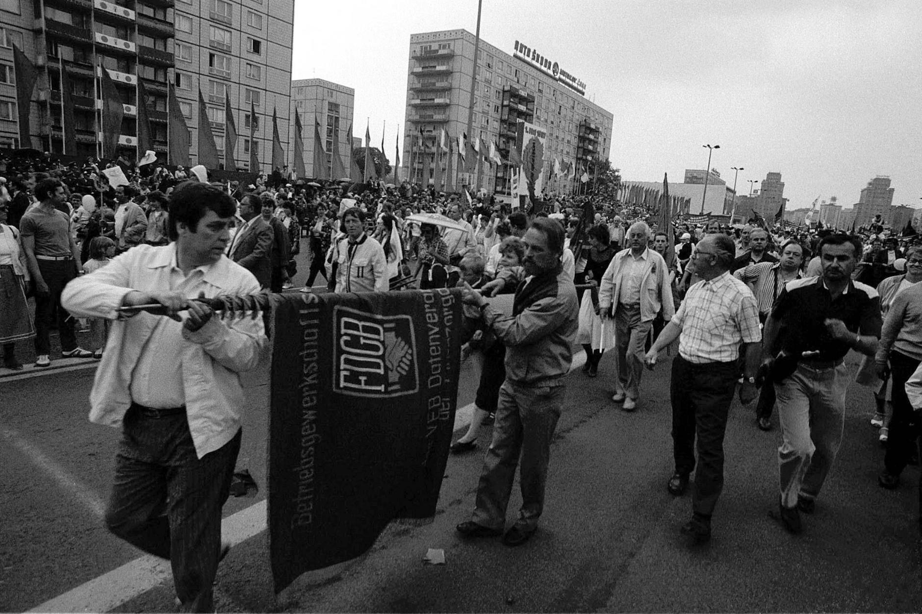 DDR, Berlin, Alexanderplatz, DDR-Bürger bei der Demonstration am 1. Mai 1987, Männer rollen eine FDGB Fahne ein.