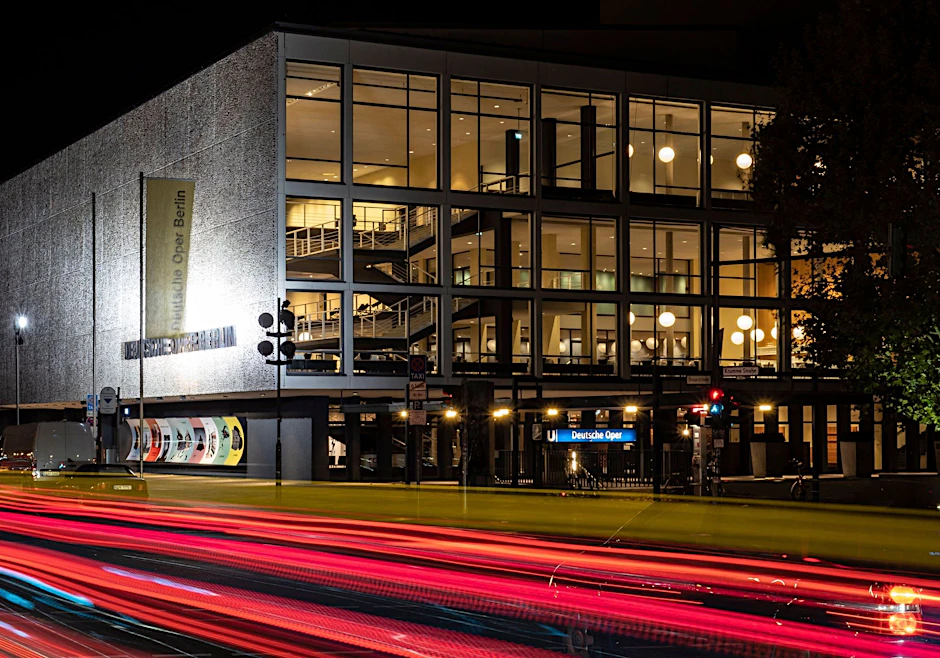 ARCHIV - Vorbeifahrende Fahrzeuge erzeugen vor der Deutschen Oper Berlin rote Lichtstreifen.  
