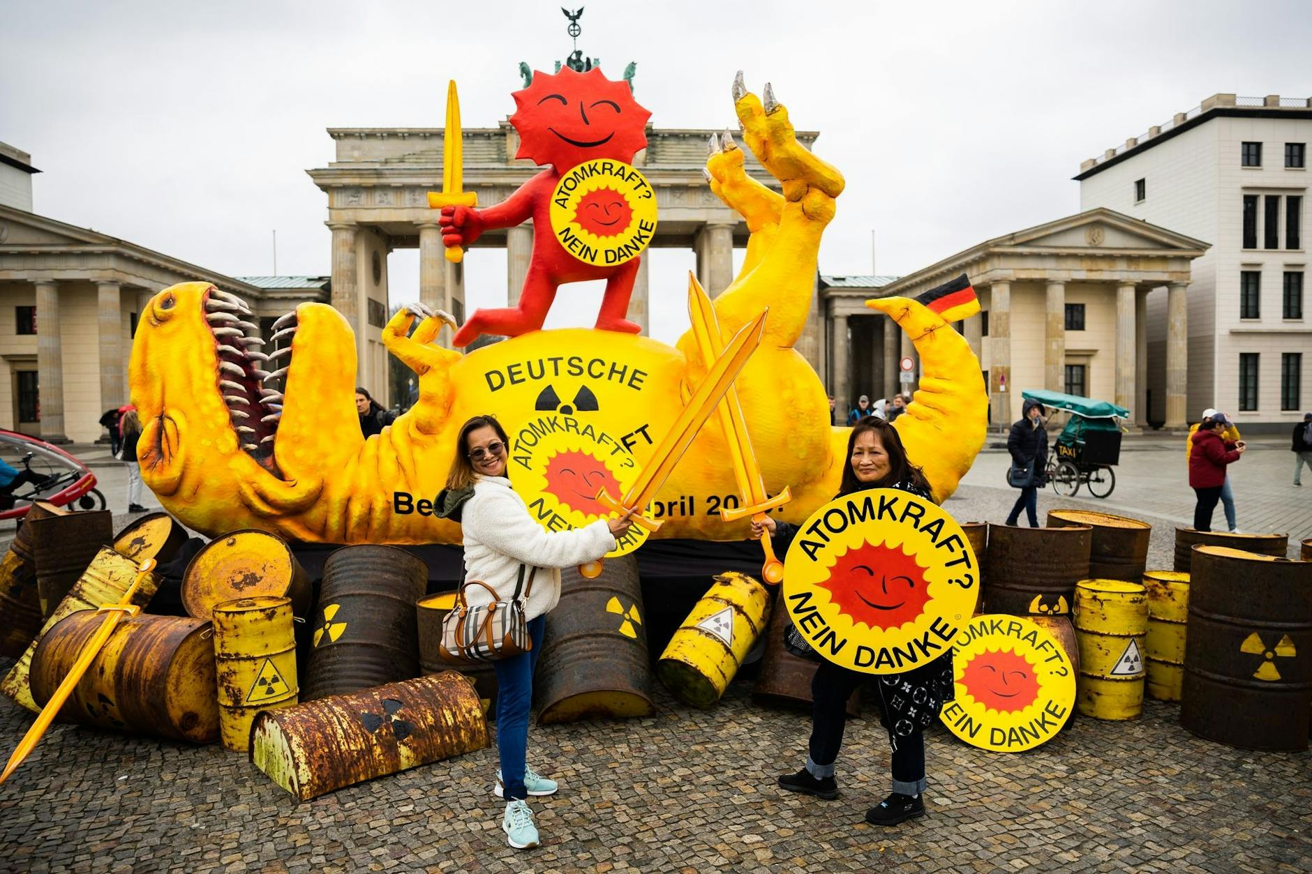 dpatopbilder - Touristen von den Philippinen posieren mit Schwertern und Schildern vor einer Dinosaurier-Figur und der roten Sonne.