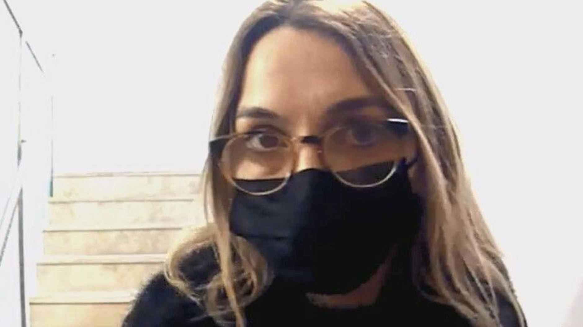 Die zweite Tatverdächtige trägt eine Corona-Maske, steht direkt vor der Tür.