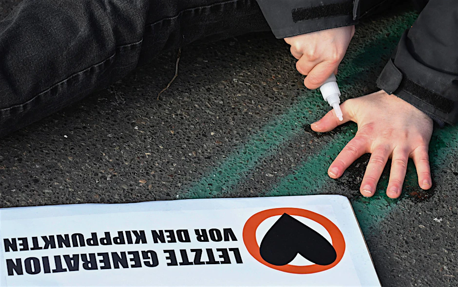Ein Aktivist der Letzten Generation klebt sich an einer Straße fest.