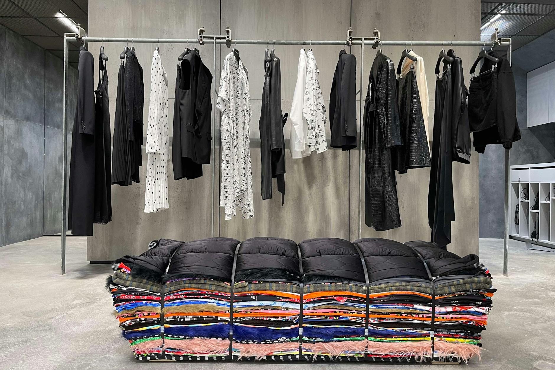 Ein Blick auf die Balenciaga-Bank des niederländischen Künstlers Tejo Remy, dahinter Teile der aktuellen Kollektion, drumherum Beton. 