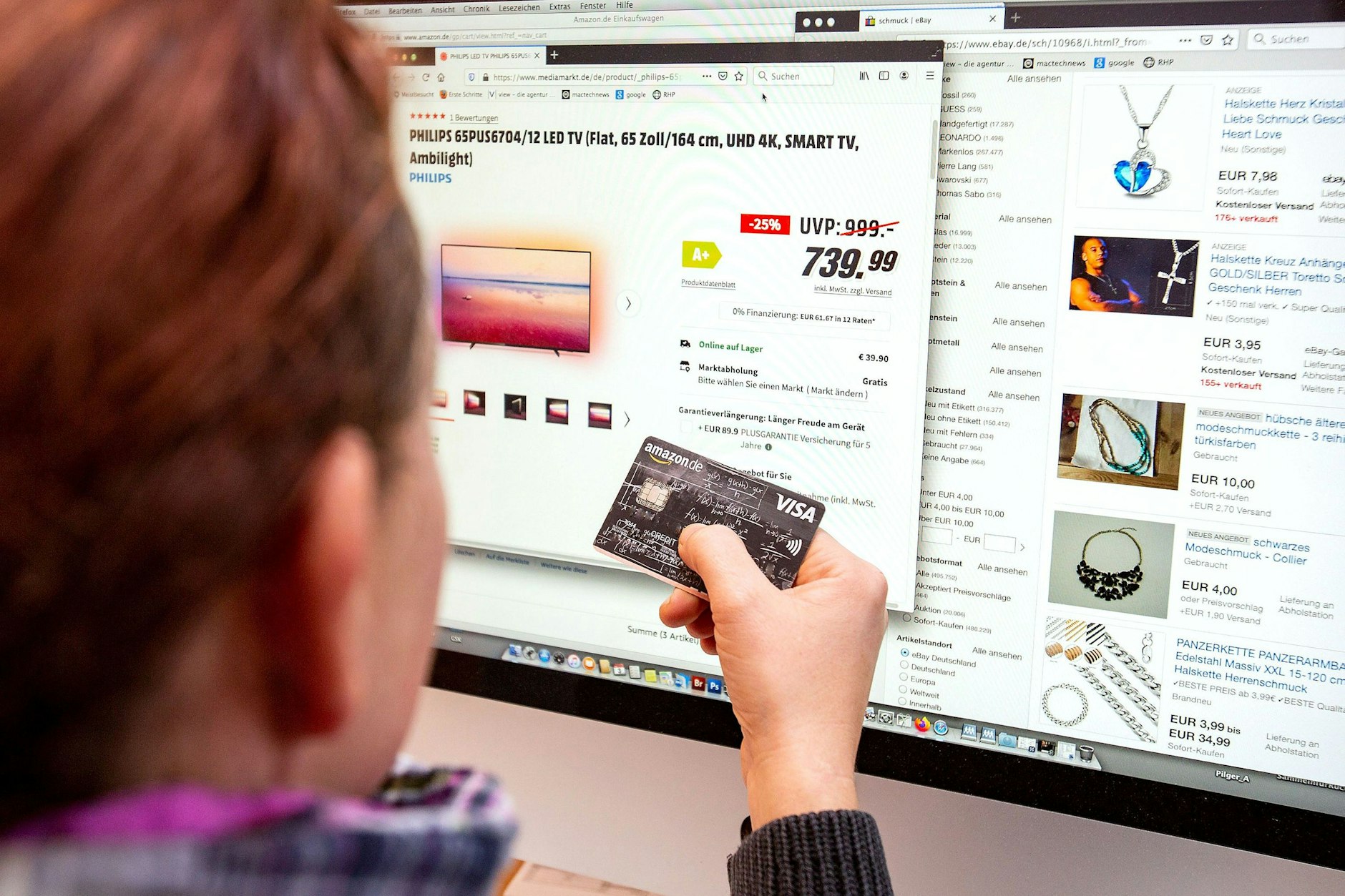 Ein Mann mit einer Kreditkarte am PC-Bildschirm.