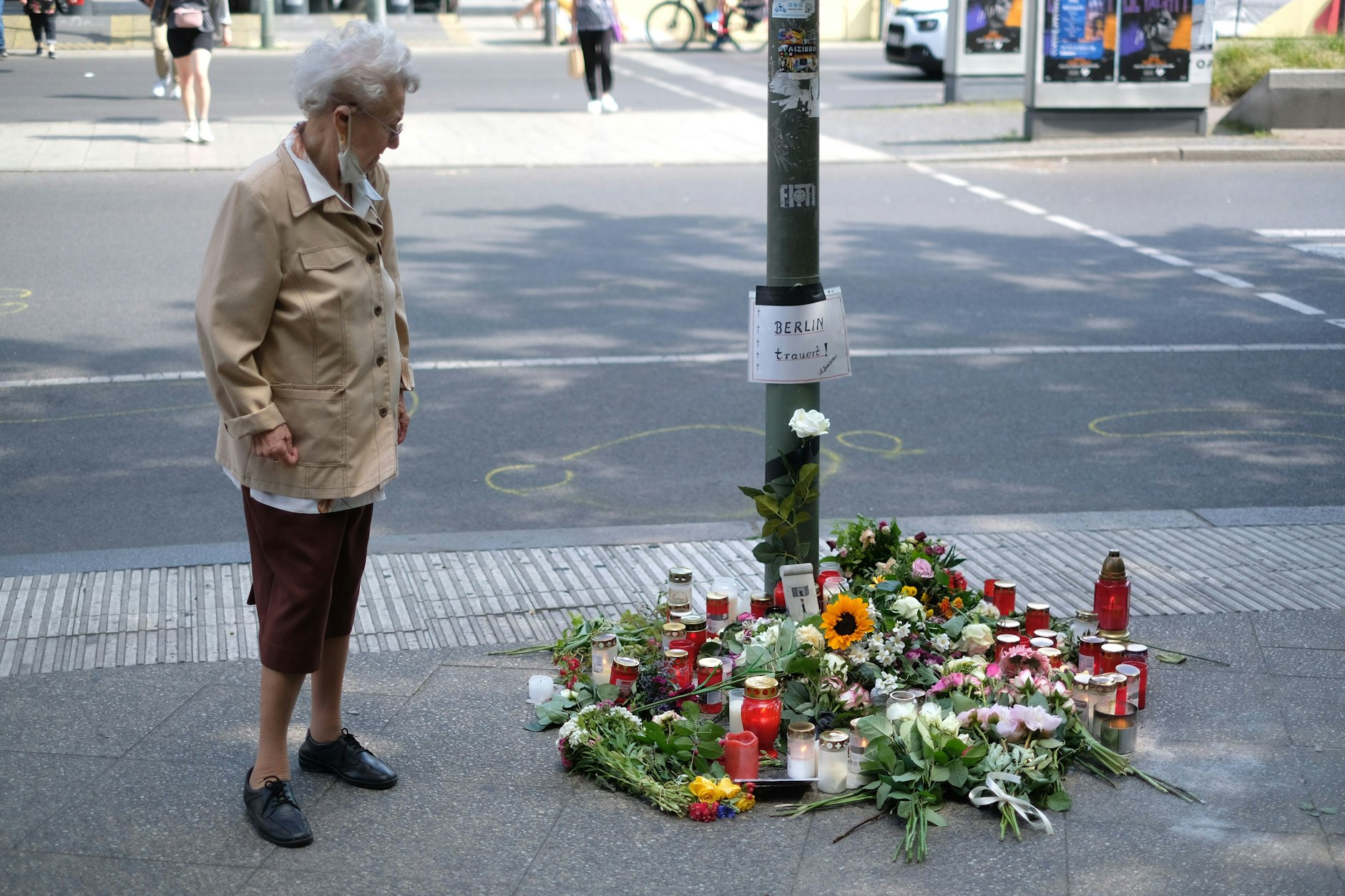 Eine Passantin geht an der Unglücksstelle&nbsp; vorüber. Menschen haben am Kudamm Blumen abgelegt.&nbsp;