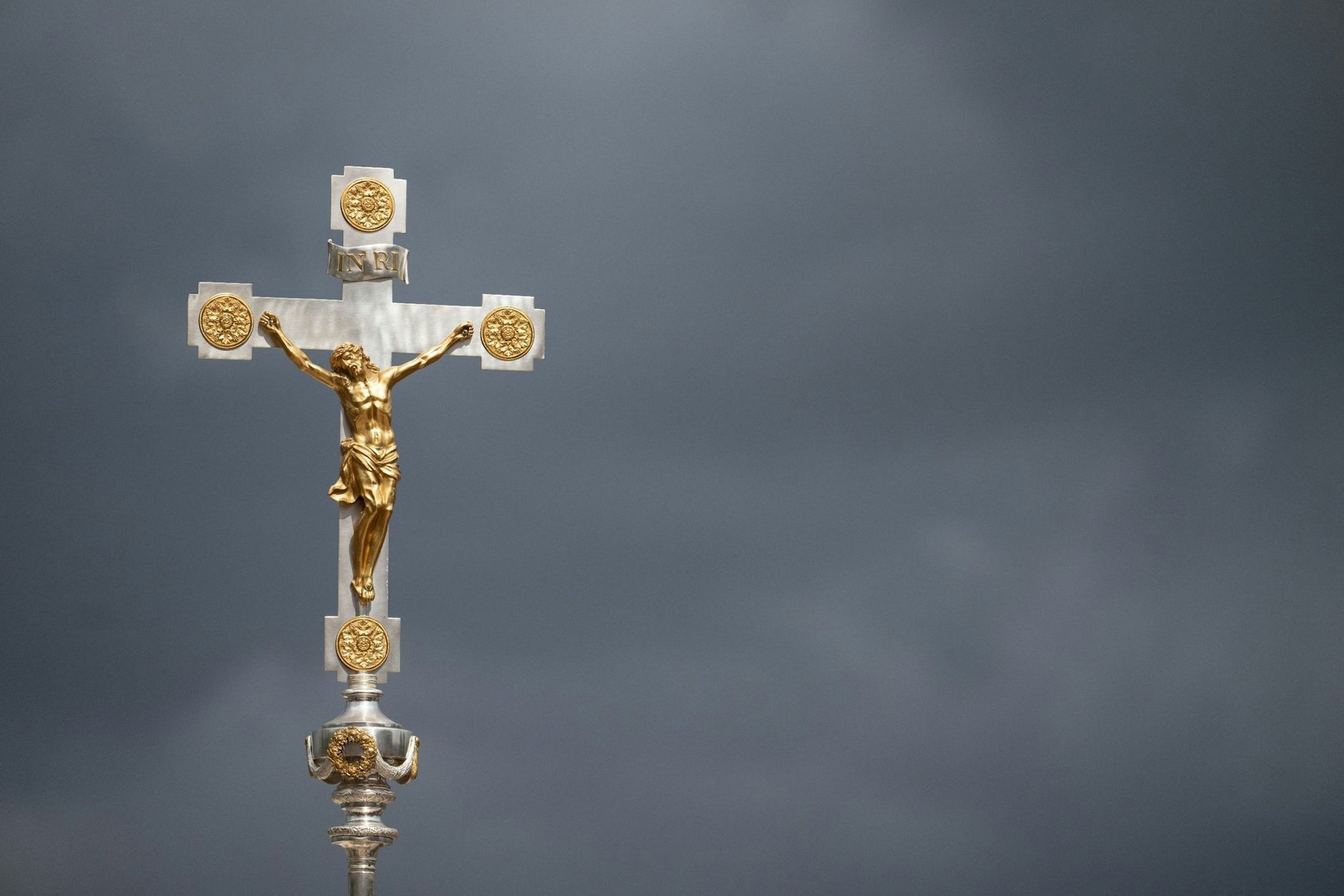 Ein katholisches Kruzifix ist vor dunklen Wolken zu sehen.