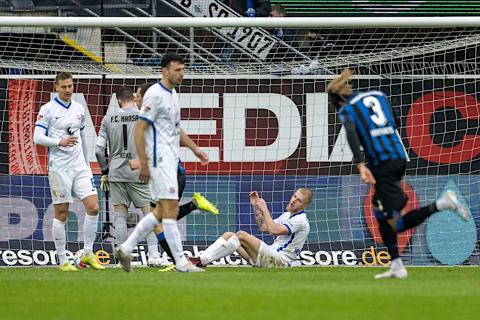Rostocks Rick van Drongelen (2.v.r.) sitzt nach dem Tor zum 0:1-Rückstand auf dem Rasen.  