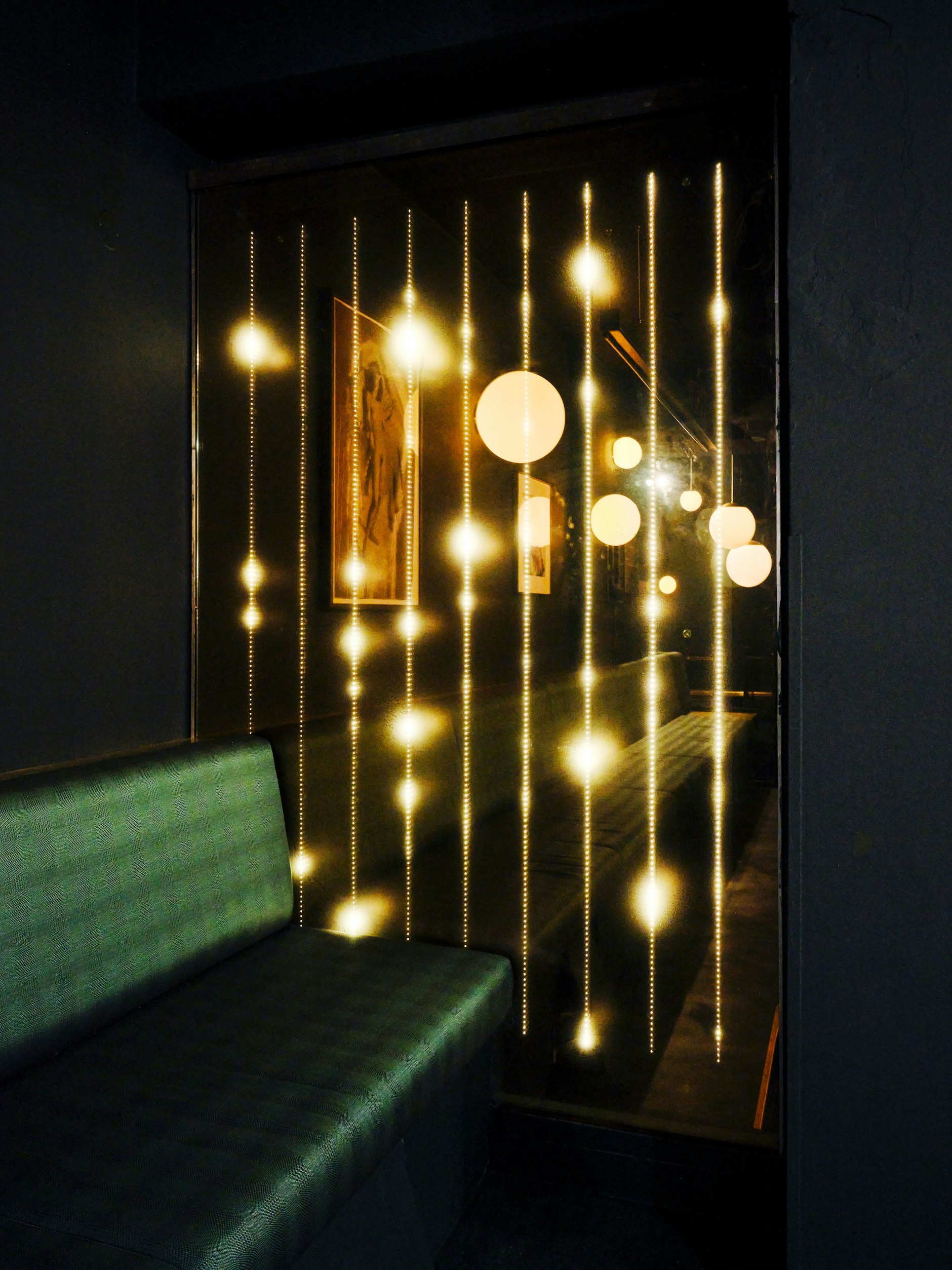 LED-Goldregen, der an den alten Fensterscheiben des Palasts der Republik hinabläuft. Im Glas spiegeln sich die in „British Racing Green“ bezogenen Bänke.&nbsp;