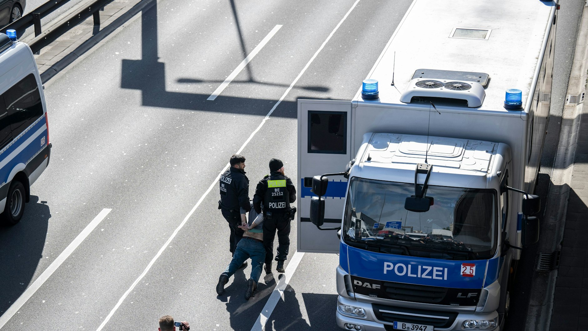 Zwei Polizisten tragen einen Aktivisten zum Gefangenentransport auf der A100.&nbsp;