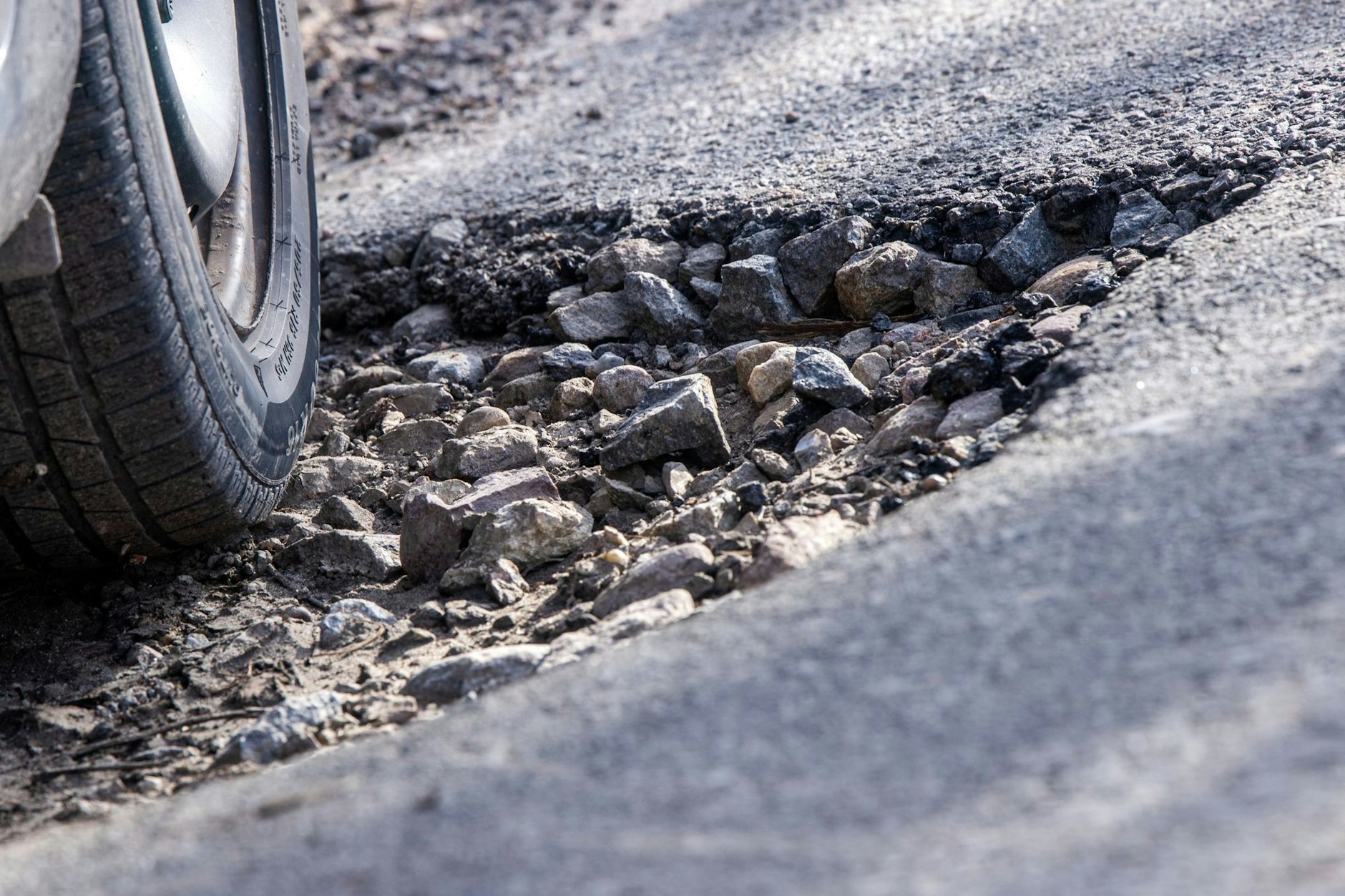 Ein Auto fährt durch ein Schlagloch: Aber wer haftet, wenn es dabei zu einem Schaden kommt?