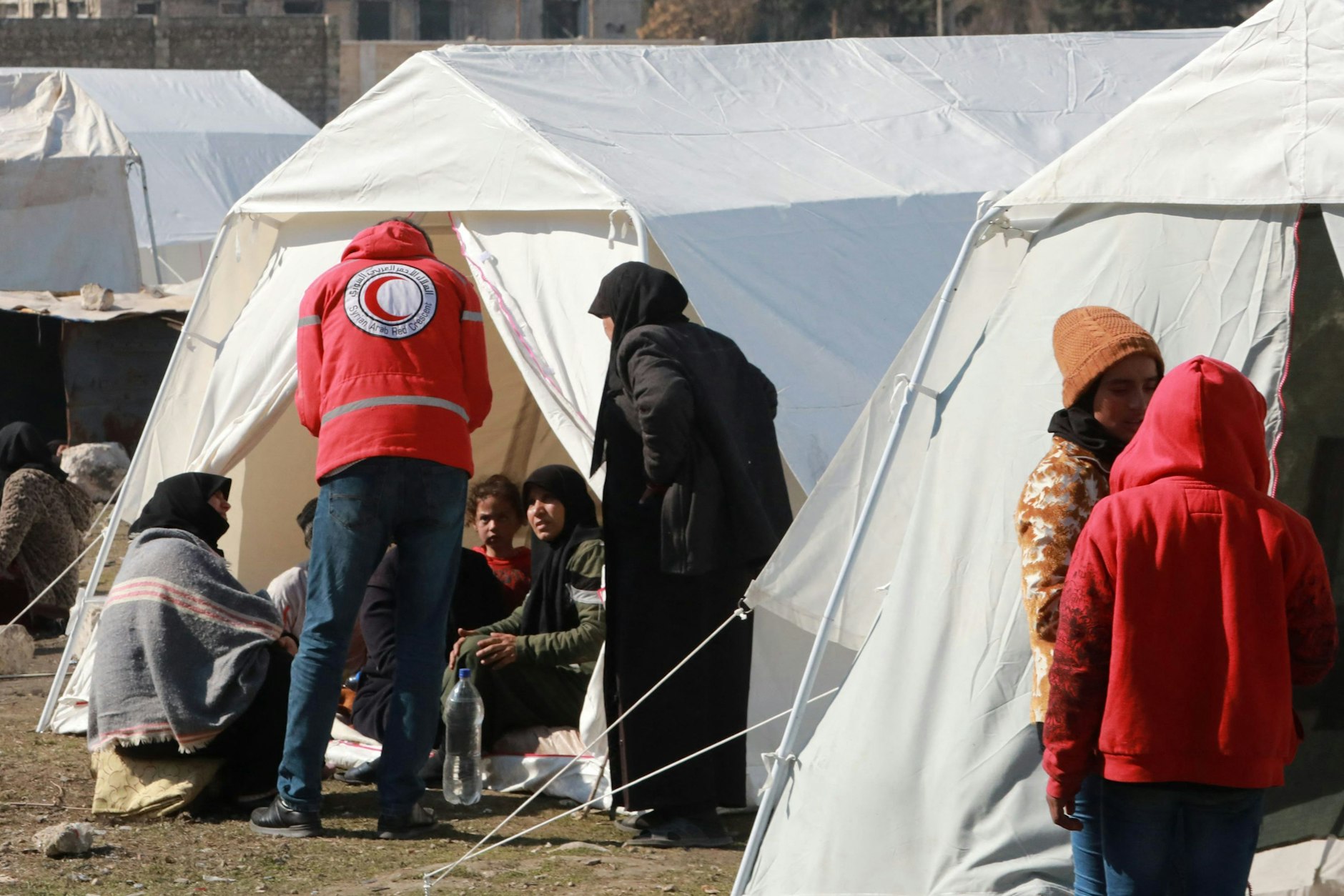 Mitglieder des Syrisch-Arabischen Roten Halbmonds mit Menschen, die bei dem verheerenden Erdbeben ihre Häuser verloren haben.