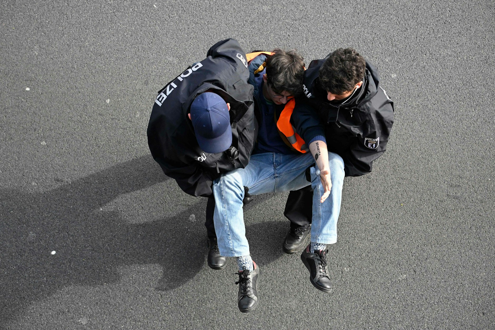 Ein Klimaaktivist der Letzten Generation wird von Polizisten weggetragen. Bei einigen Protesten der Gruppe soll es auch zu Sabotage-Aktionen auf Firmengeländen gekommen sein.