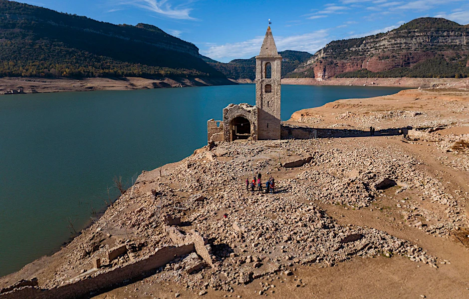 ARCHIV - Normalerweise von Wasser bedeckt: Eine Kirche und die Überreste eines alten Dorfes im Stausee von Sau in Spanien.  